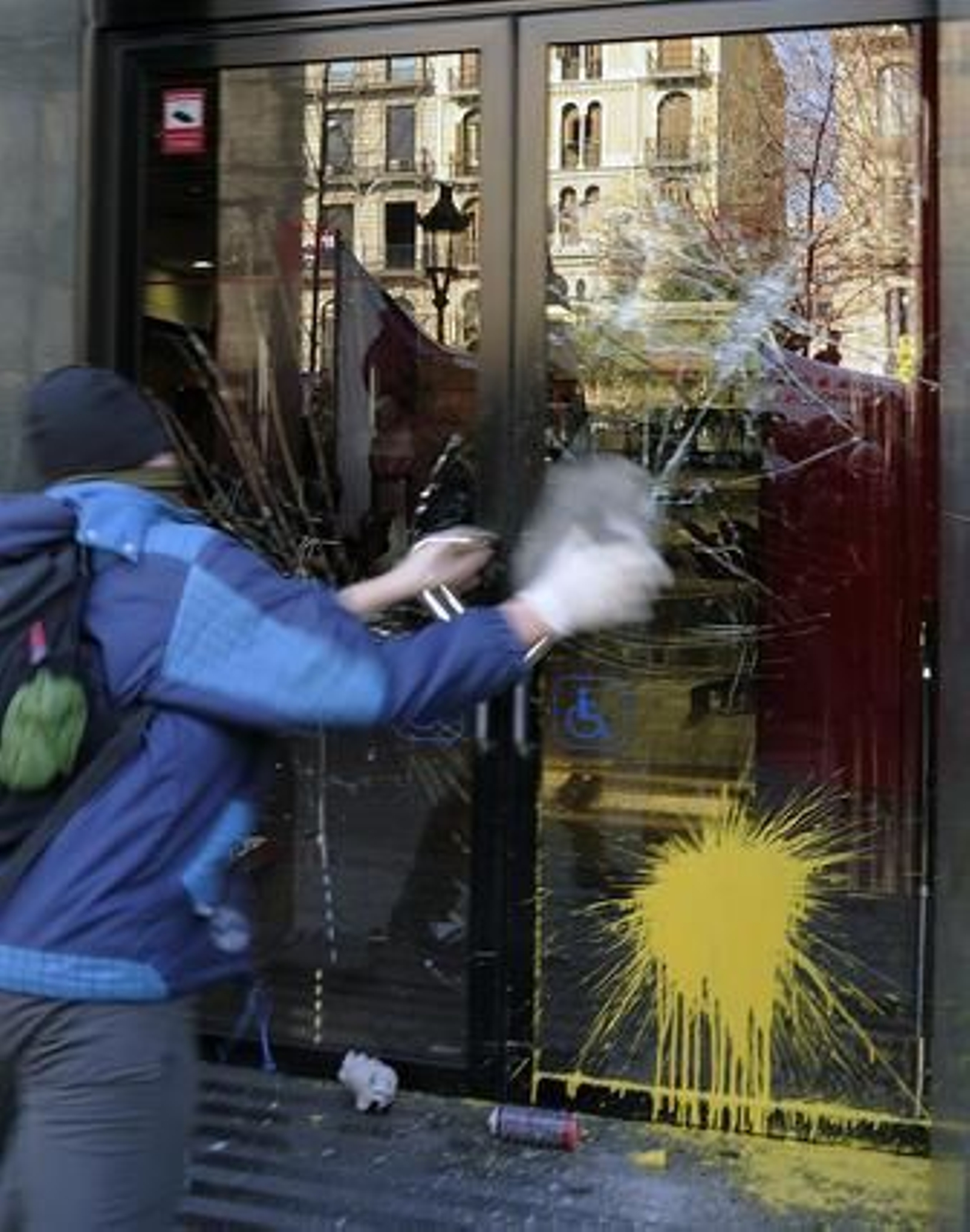 Un joven lanza piedras y bolas de pintura contra un banco.

Foto: AFP Photo