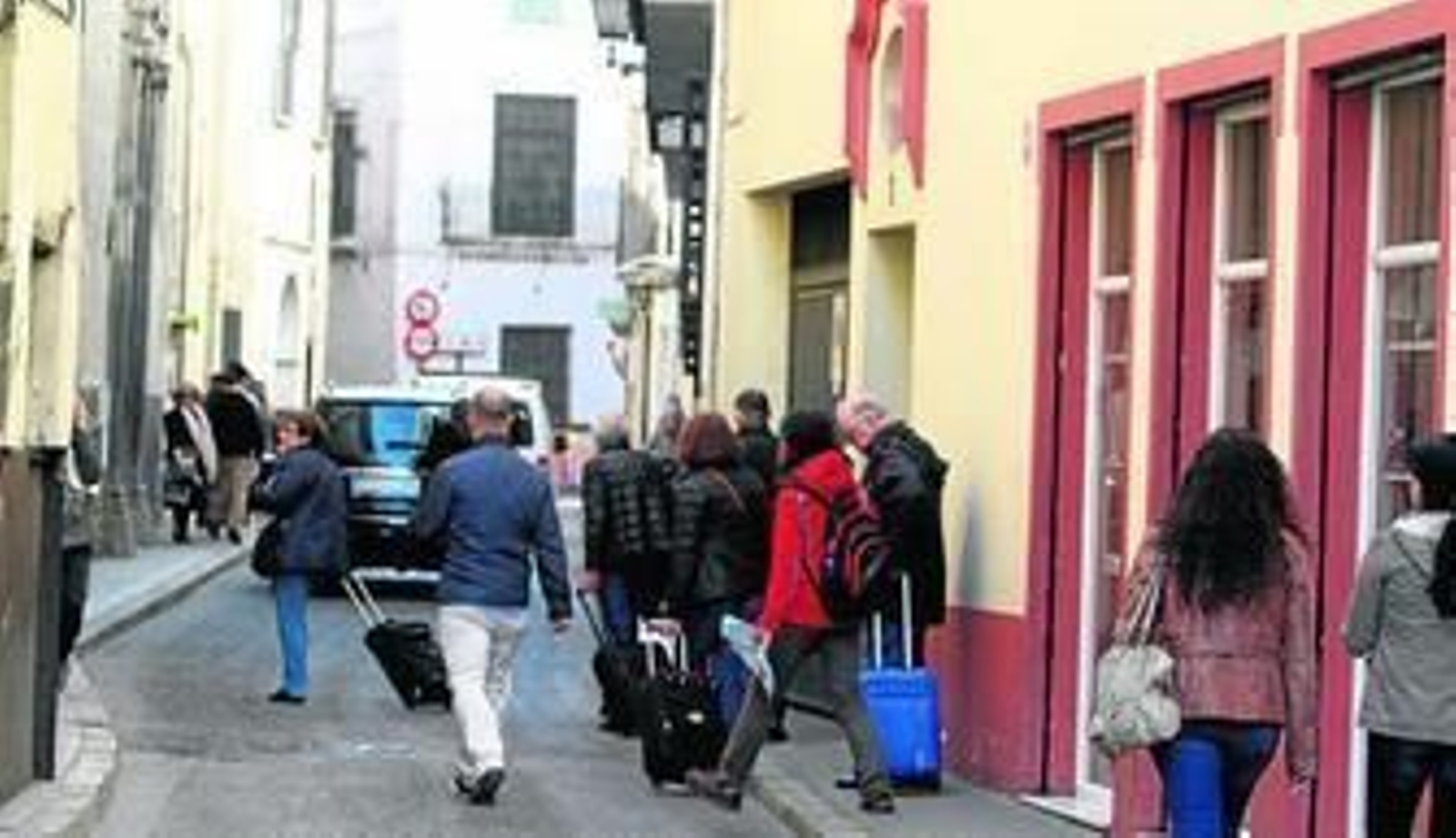 Varios turistas caminan con sus maletas por la calzada de Águilas.