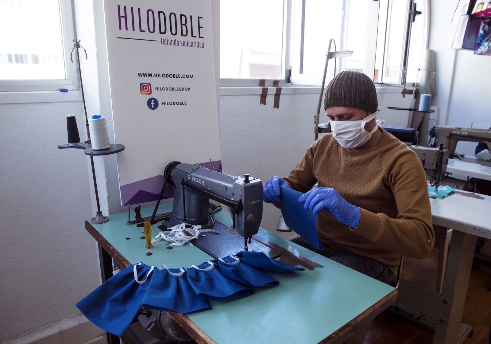 Una persona en riesgo de exclusión fabricando mascarillas, gracias a una iniciativa de la Diputación de Málaga con la colaboración de CaixaBank y Fundación Bancaria "La  Caixa".