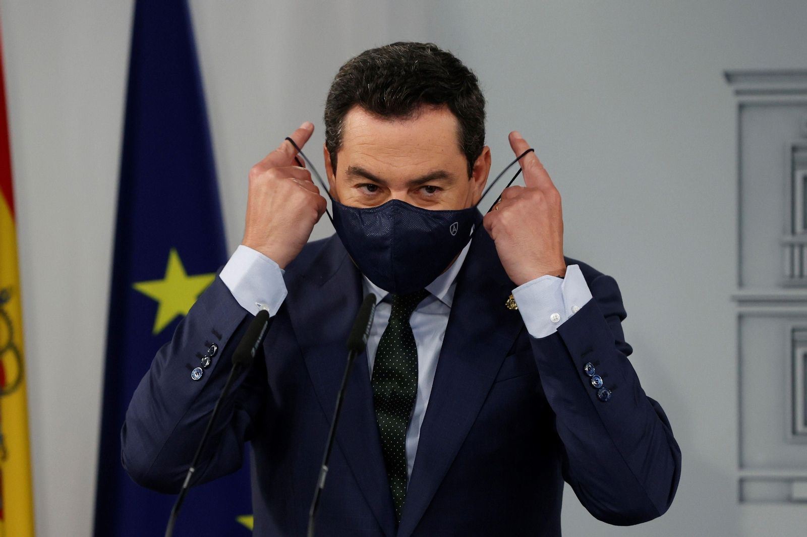 Juanma Moreno se coloca la mascarilla.