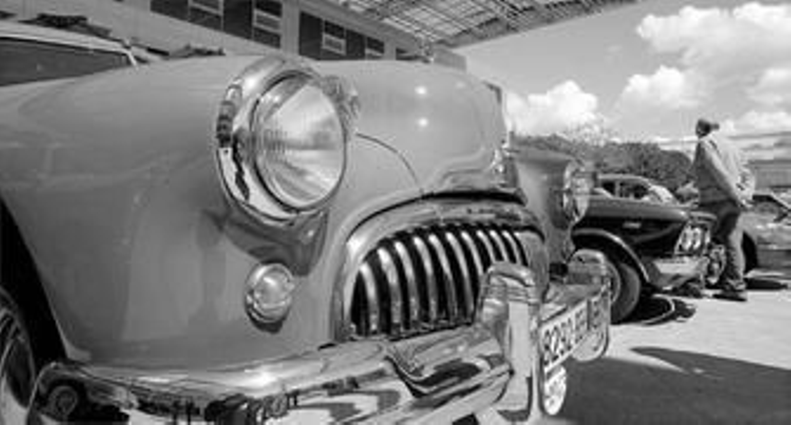 Un visitante observa la exposición de coches; en primer término el Buick Eight de 1947.