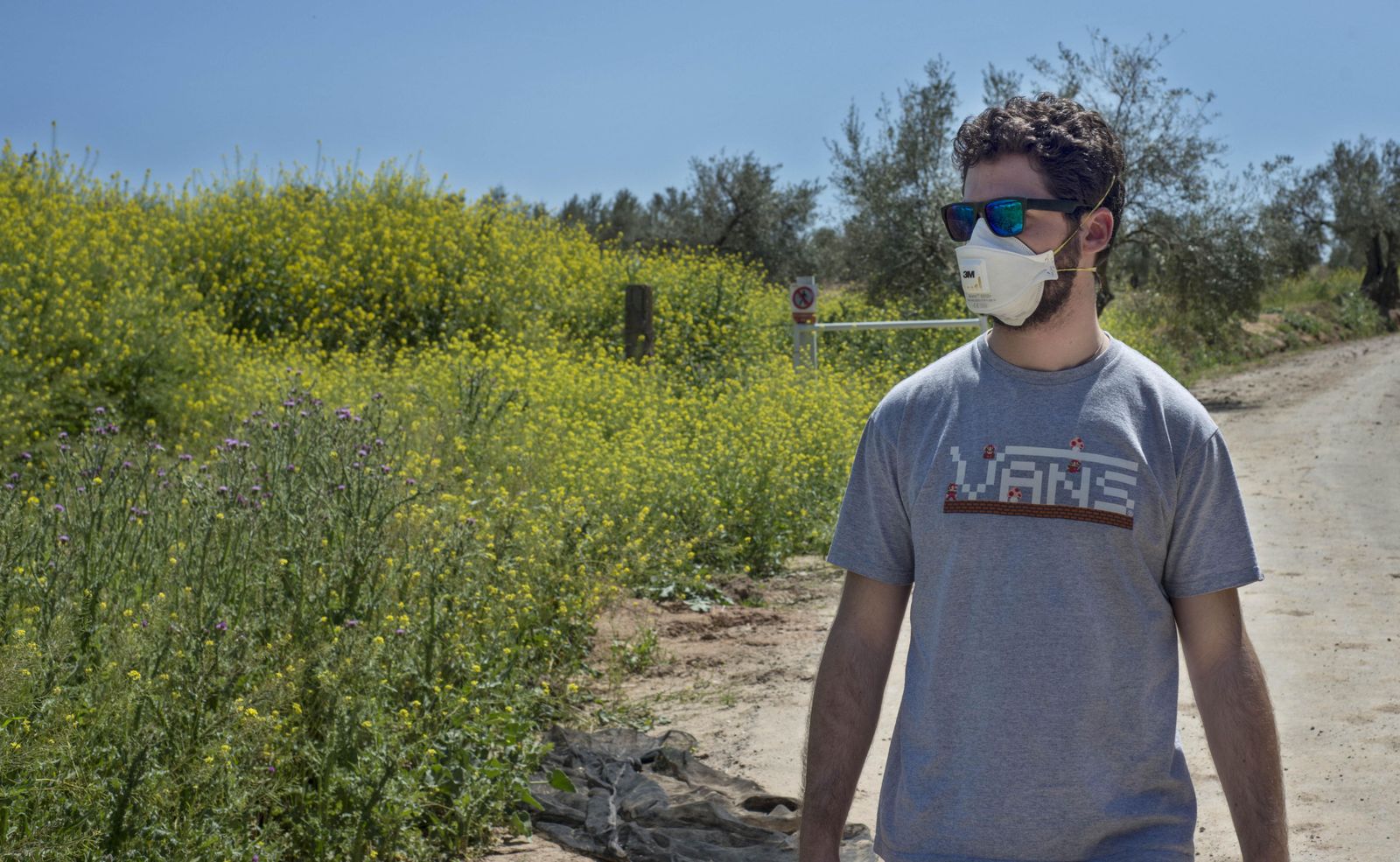 Un joven pasea por el campo con una mascarilla puesta.