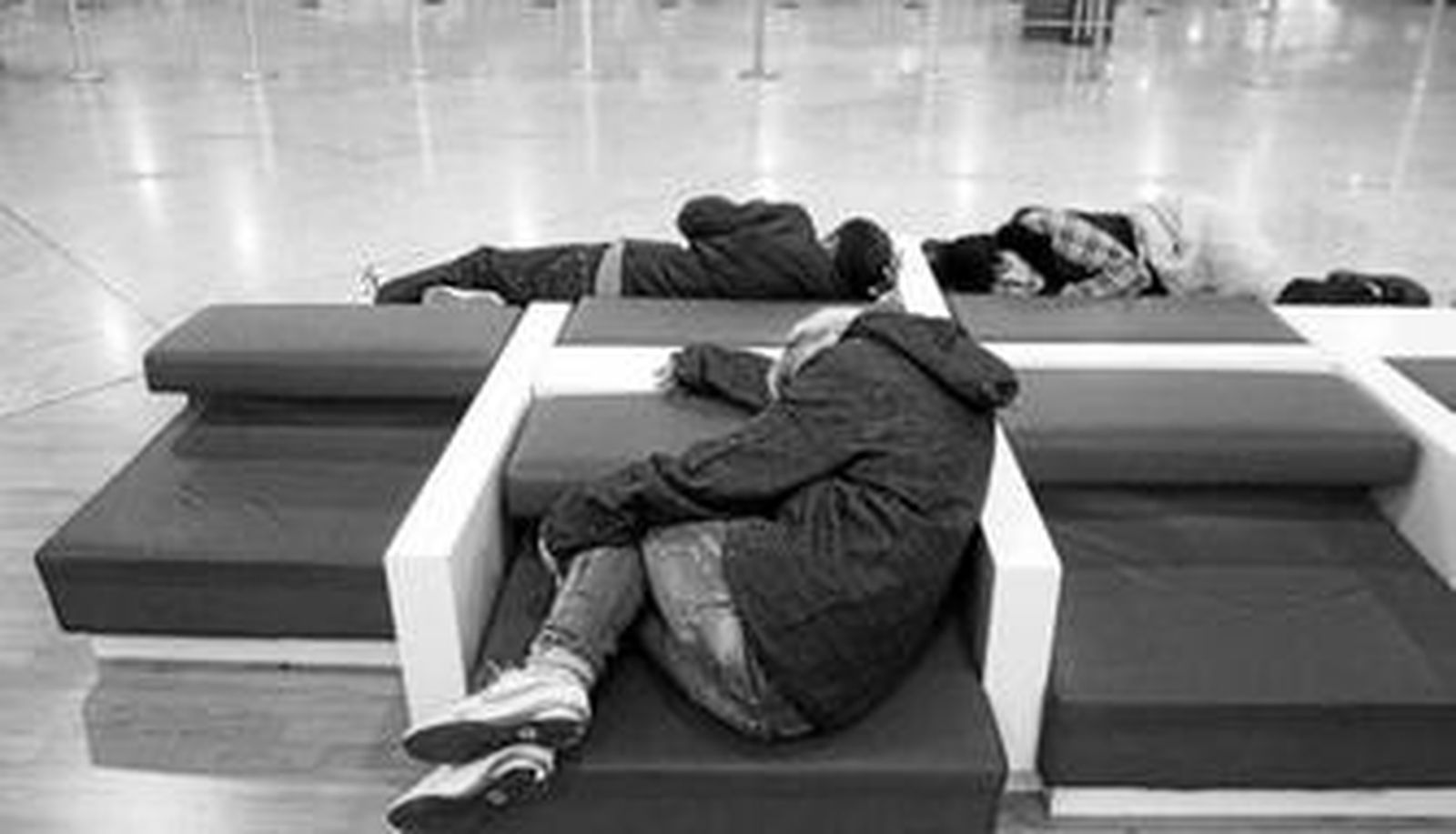 Varias personas duermen en el vestíbulo de un aeropuerto.