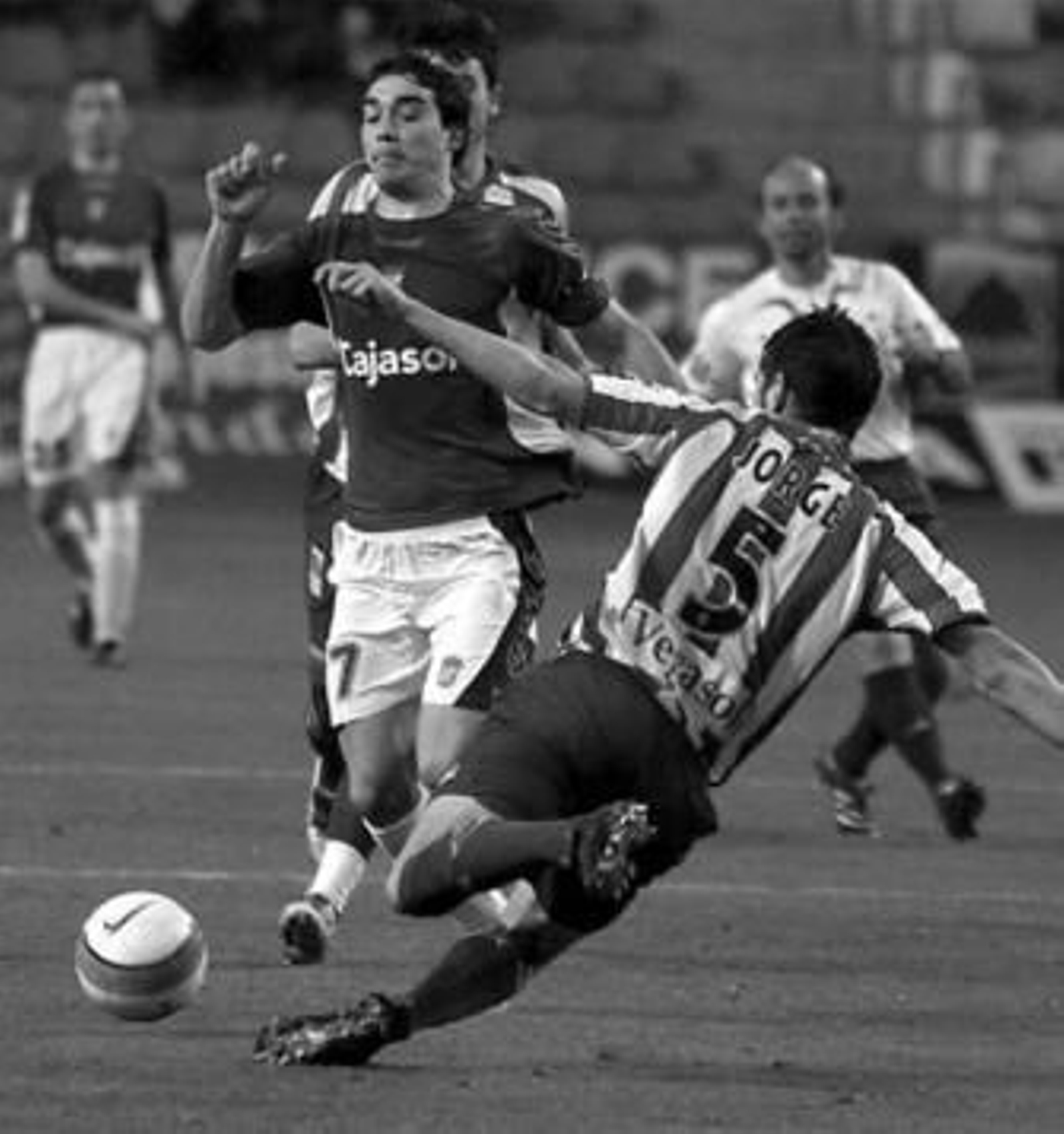 1. El jerezano Juan Antonio Portela regresó al equipo titular después de quedarse en la grada la semana pasada. El canterano hizo funciones de lateral izquierdo mientras Mendoza ocupó la banda derecha muchos años después. 2. Francis fue la gran novedad en la alineación de Esteban Vigo, principalmente porque el técnico le colocó en el centro del campo haciendo funciones de mediocentro junto a Vicente Moreno. 3. El Xerez, al igual que el Sporting de Gijón, saltó al terreno de juego luciendo brazaletes negros y una camiseta en la que podía leer el 'Ahora, Quini, ahora'. 4. Viqueira intentar tapar una de las internadas del sportinguista Kike Mateo, que consiguió el segundo gol local al rematar una falta de Pedro.  5. Pedro Ríos dialoga con el colegiado balear Rodado Rodríguez, quien también fue uno de los epicentros del partido, ya que la afición rojiblanca no le ha perdonado sus malas actuaciones en anteriores partidos. FOTOS: Lof/Photodeporte