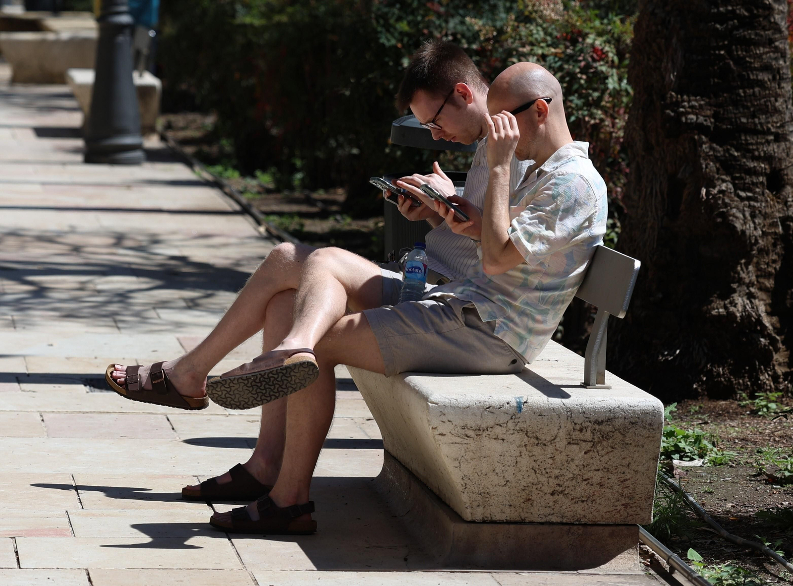 Dos personas sentadas en un banco del centro de Málaga
