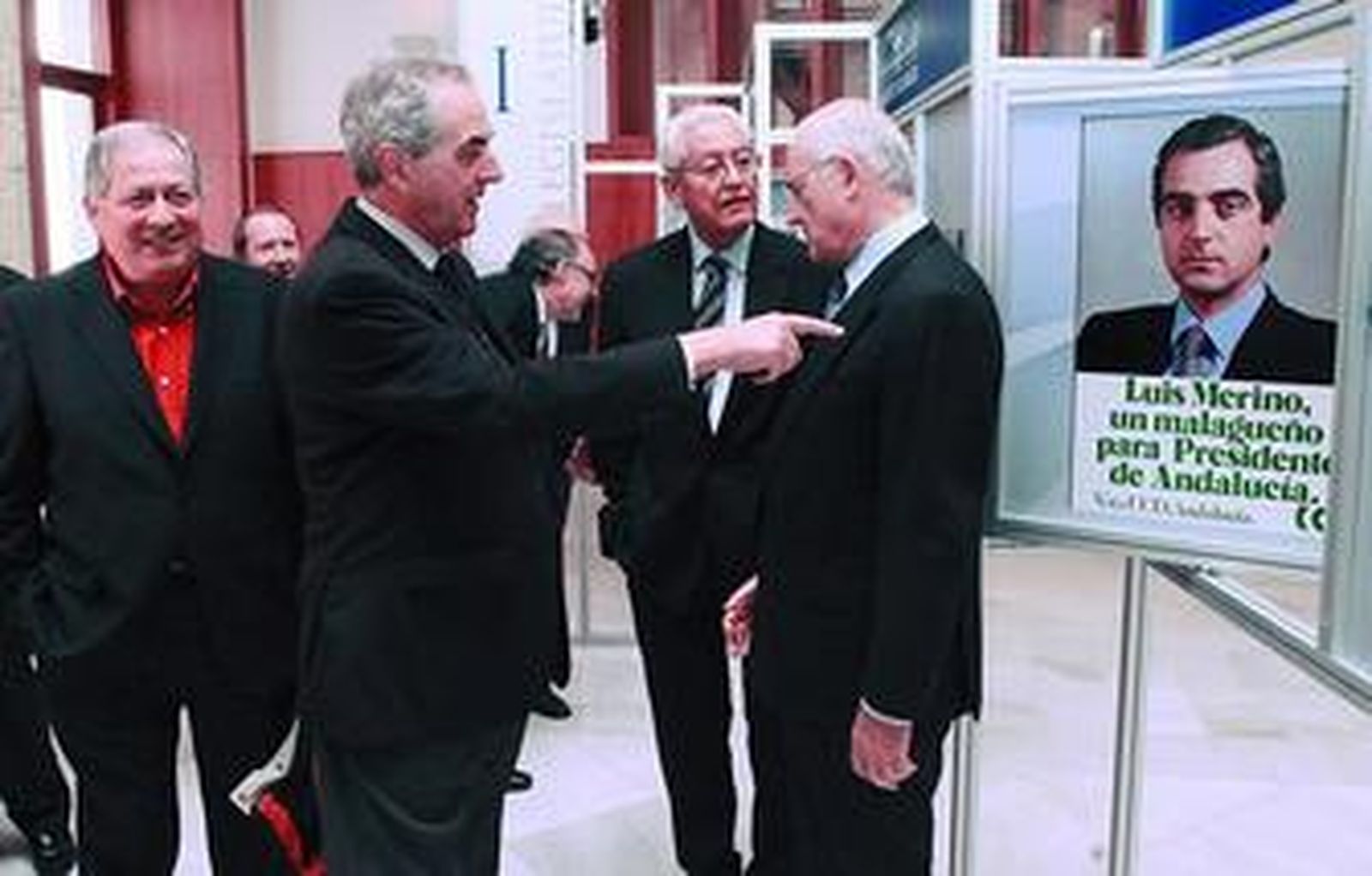 Luis Merino señala su cartel del 82 a Luis Uruñuela en el Parlamento en presencia de Felipe Alcaraz y Rafael Escuredo.