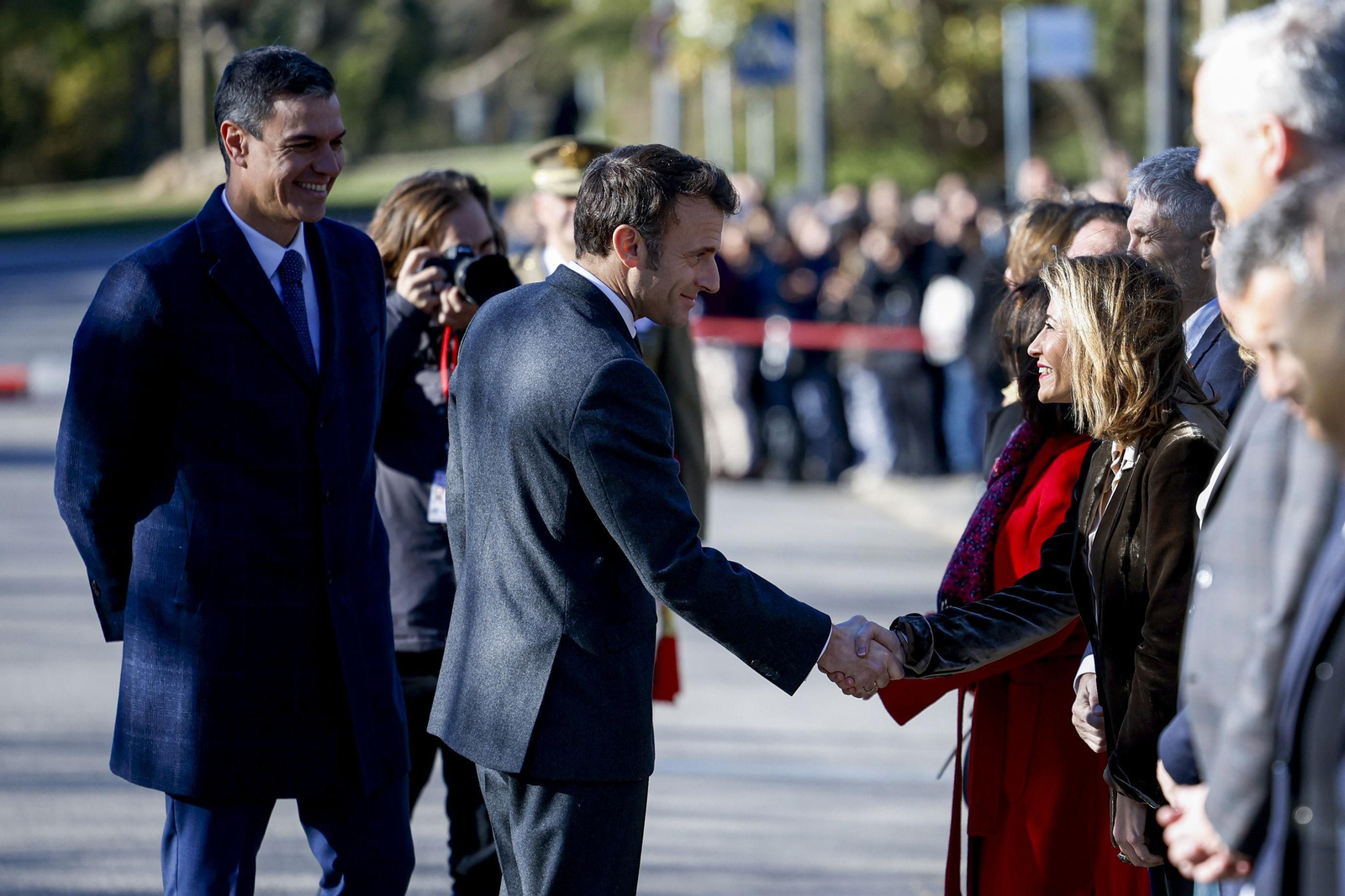 Raquel Sánchez estrecha la mano de Emmanuel Macron en presencia de Pedro Sánchez.