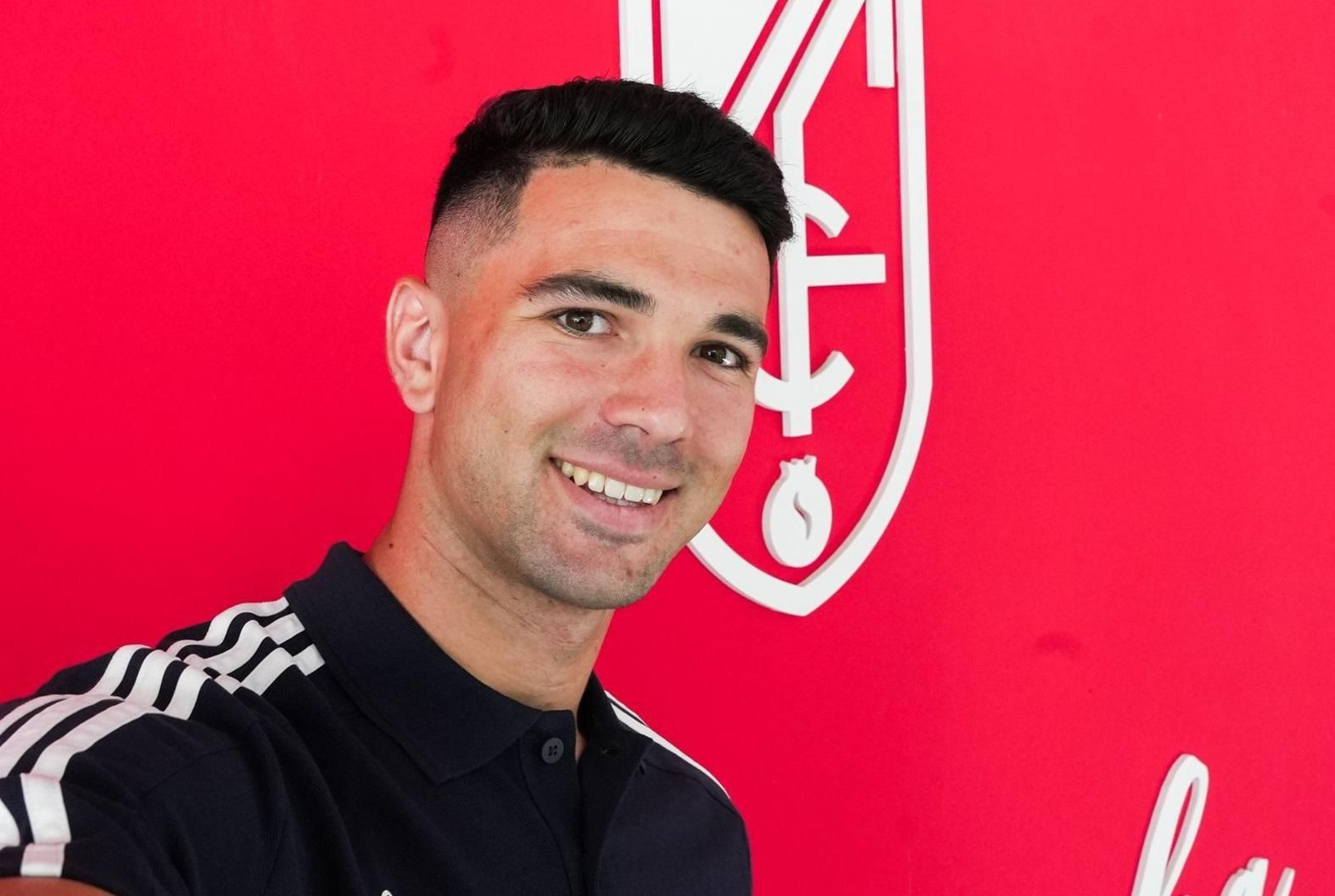 Pau Casadesús con el escudo del Granada CF detrás.