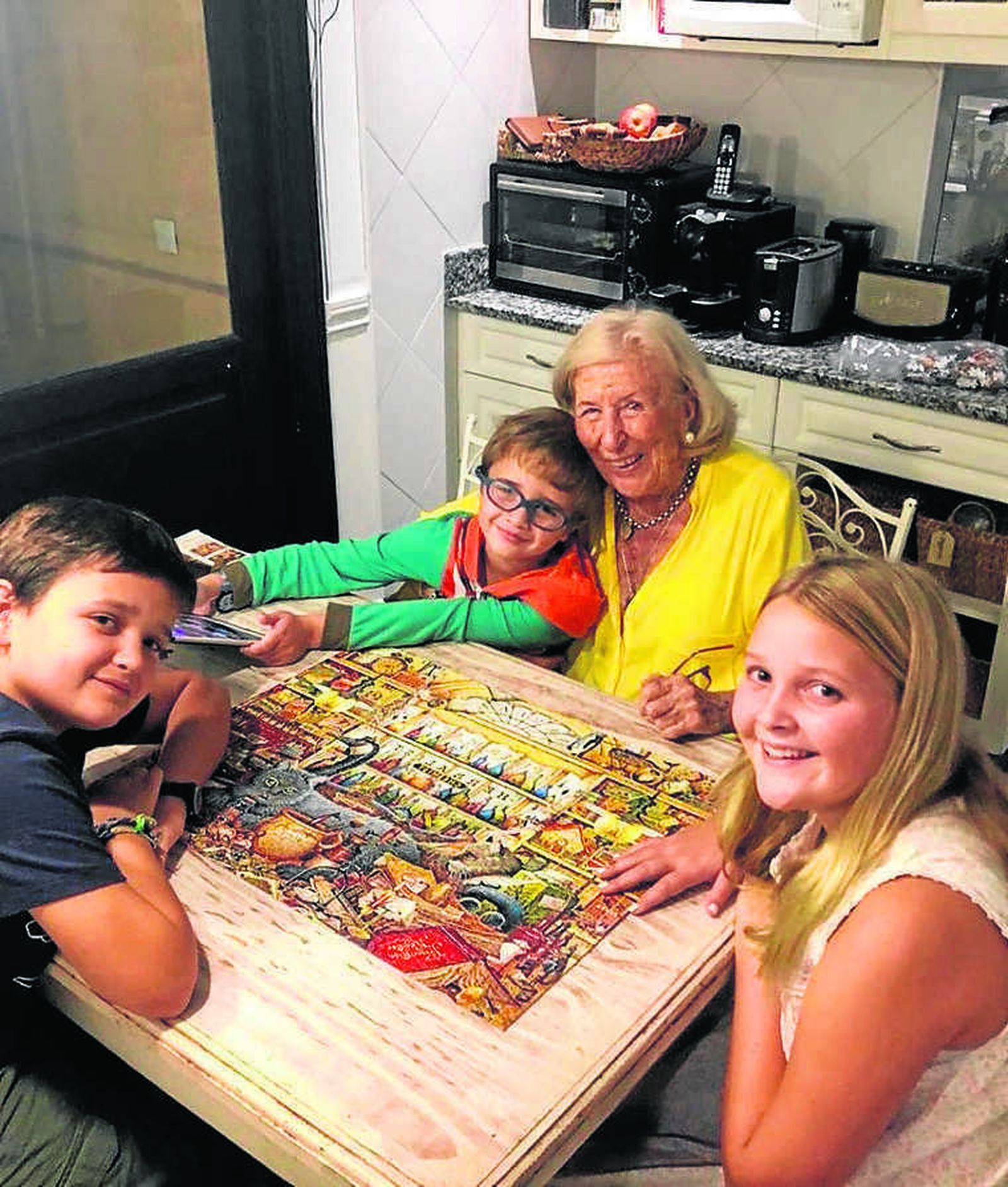 Helena Gómez, con 96 años, haciendo un puzzle  con su nietos y bisnietos,  durante su confinamiento en las afueras de Buenos Aires, Argentina