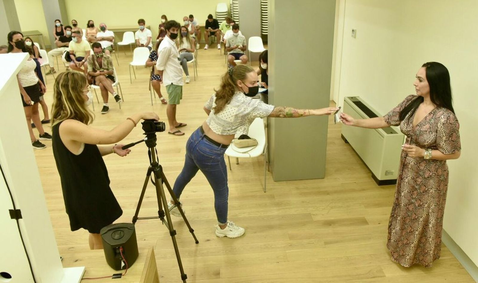 Una asistente del casting entrega a Elena su número para el proceso.