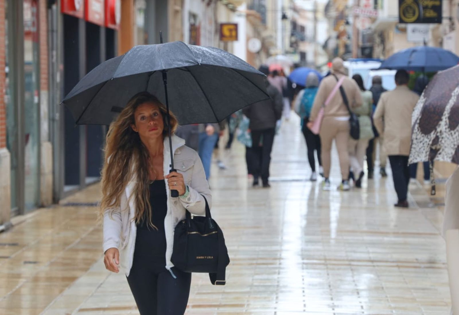 Una mujer se protege de la lluvia este jueves en Huelva.