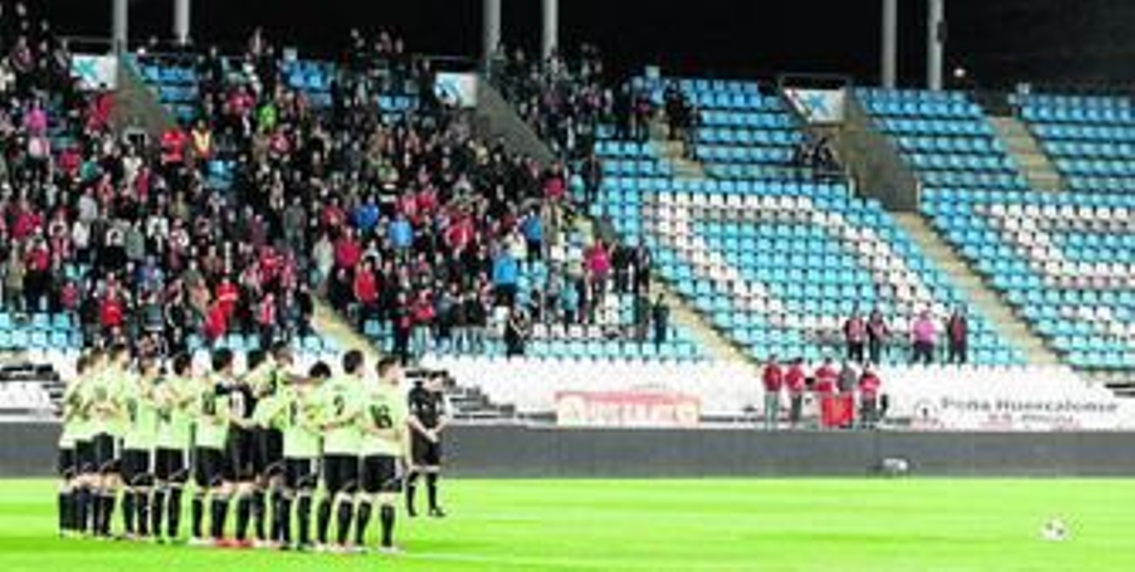 Los jugadores de Osasuna, abrazados en el centro del campo del Mediterráneo con la afición de fondo.
