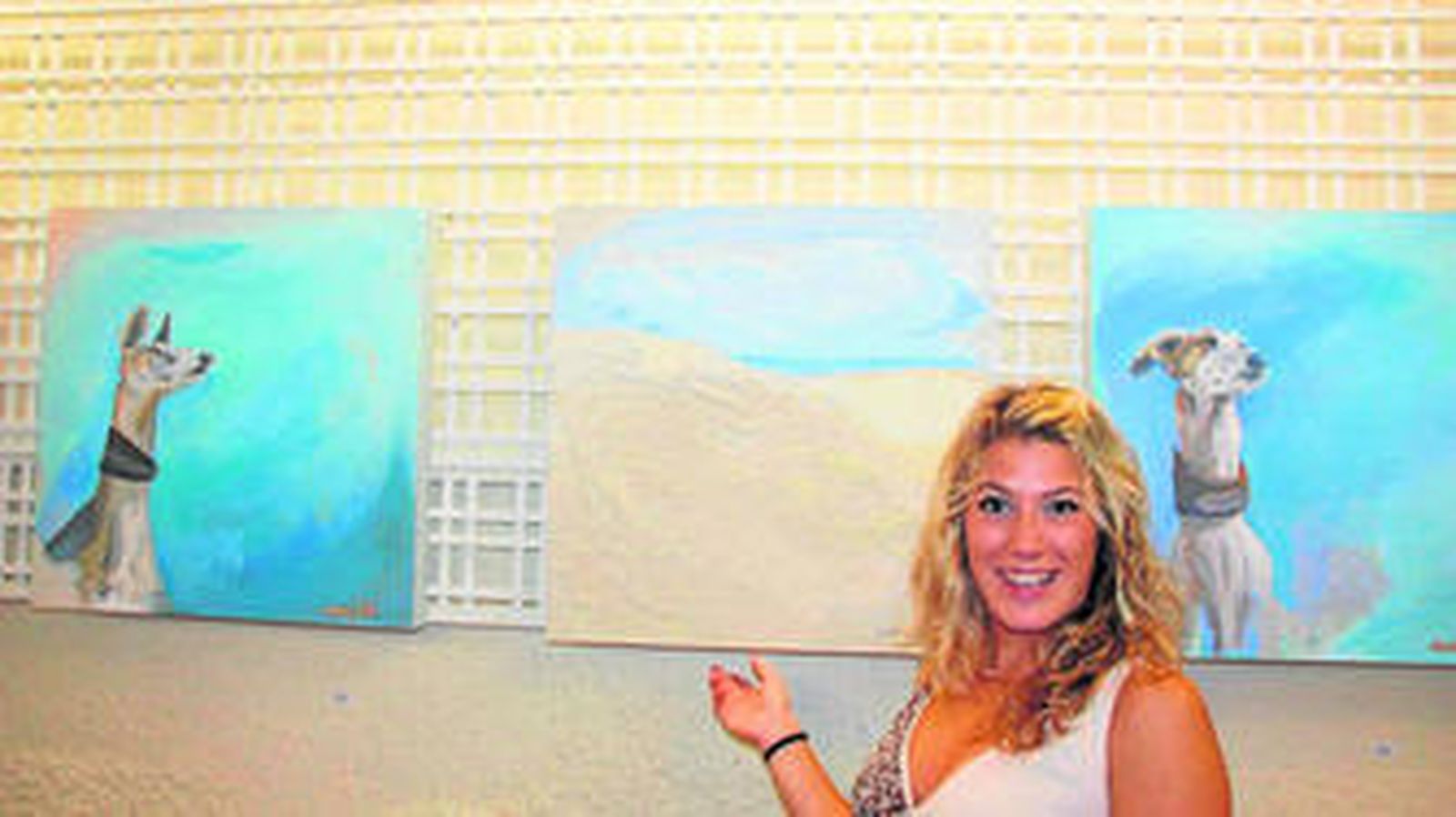 La artista Violeta Gill Díez, junto a algunos de los cuadros de su muestra en la sala del Real Club Marítimo de Tenis de Punta Umbría.