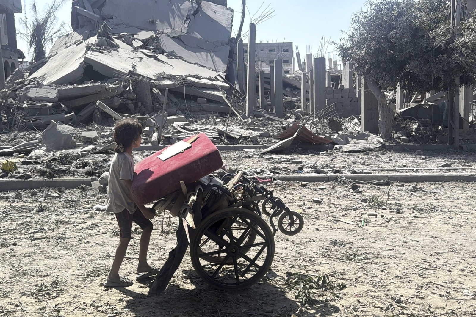 Una niña se desplaza con sus pertenencias por Ciudad de Gaza.