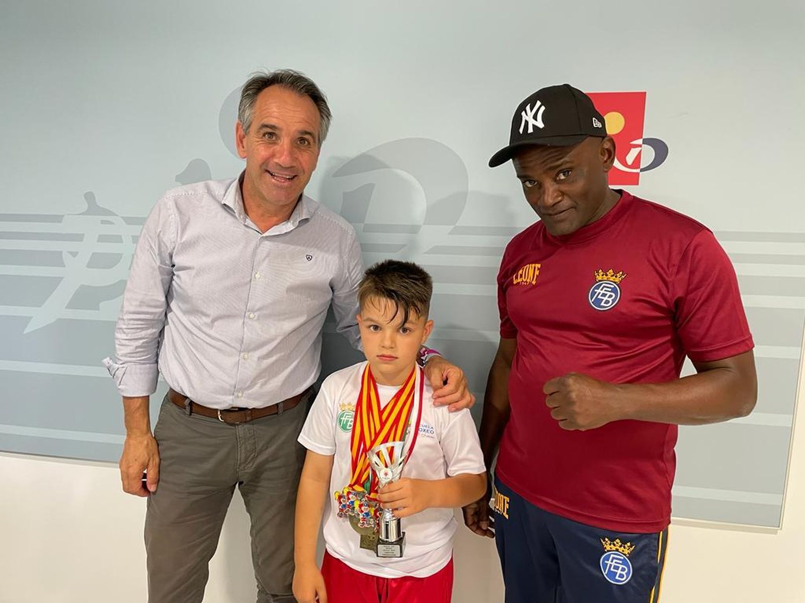 El boxeador Luka Nicolás Nerghes posa con sus medallas y trofeos junto a su entrenador y el concejal de Deportes.