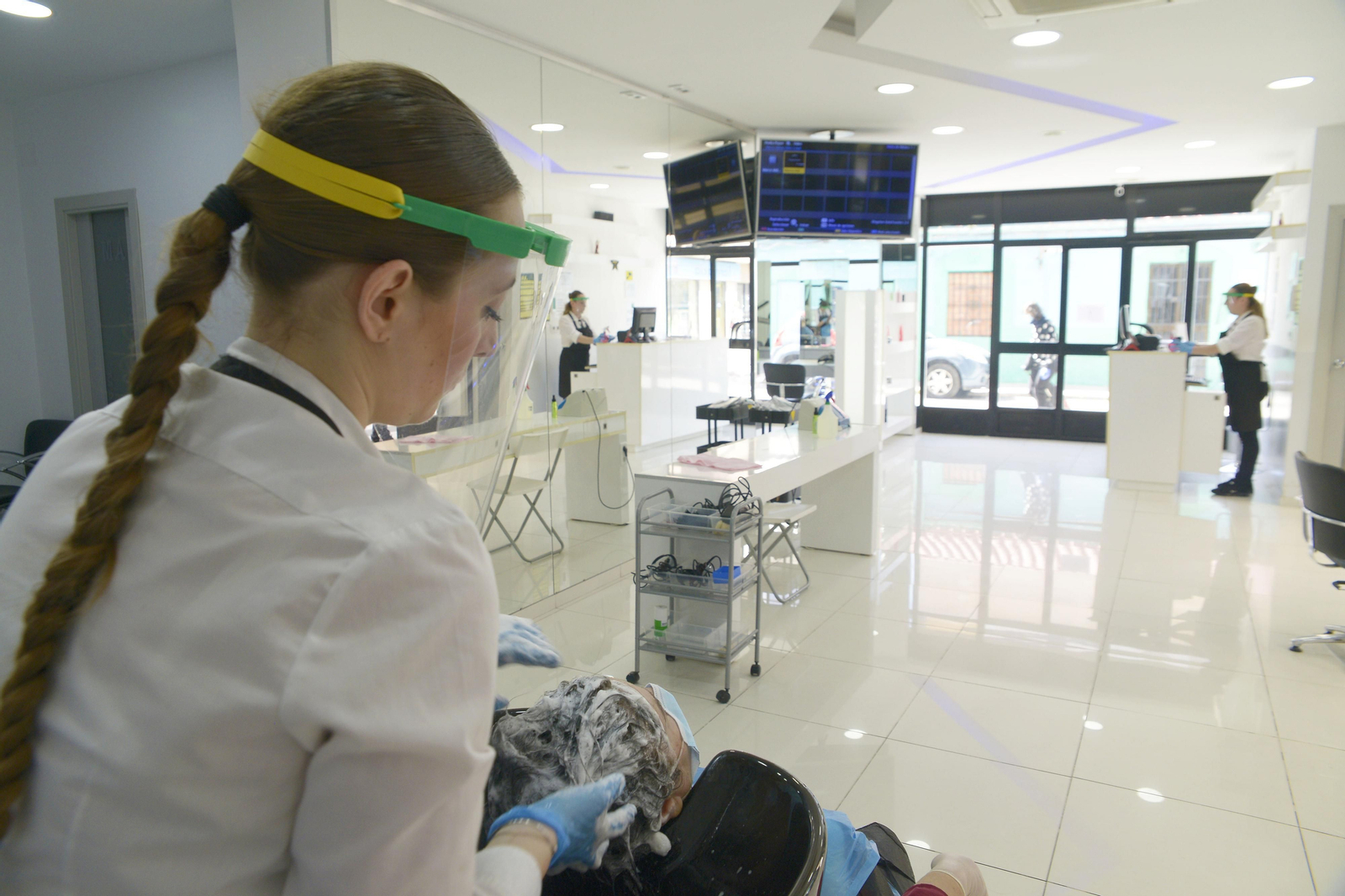 Una peluquera atiende a un cliente con pantalla facial, en La Línea.