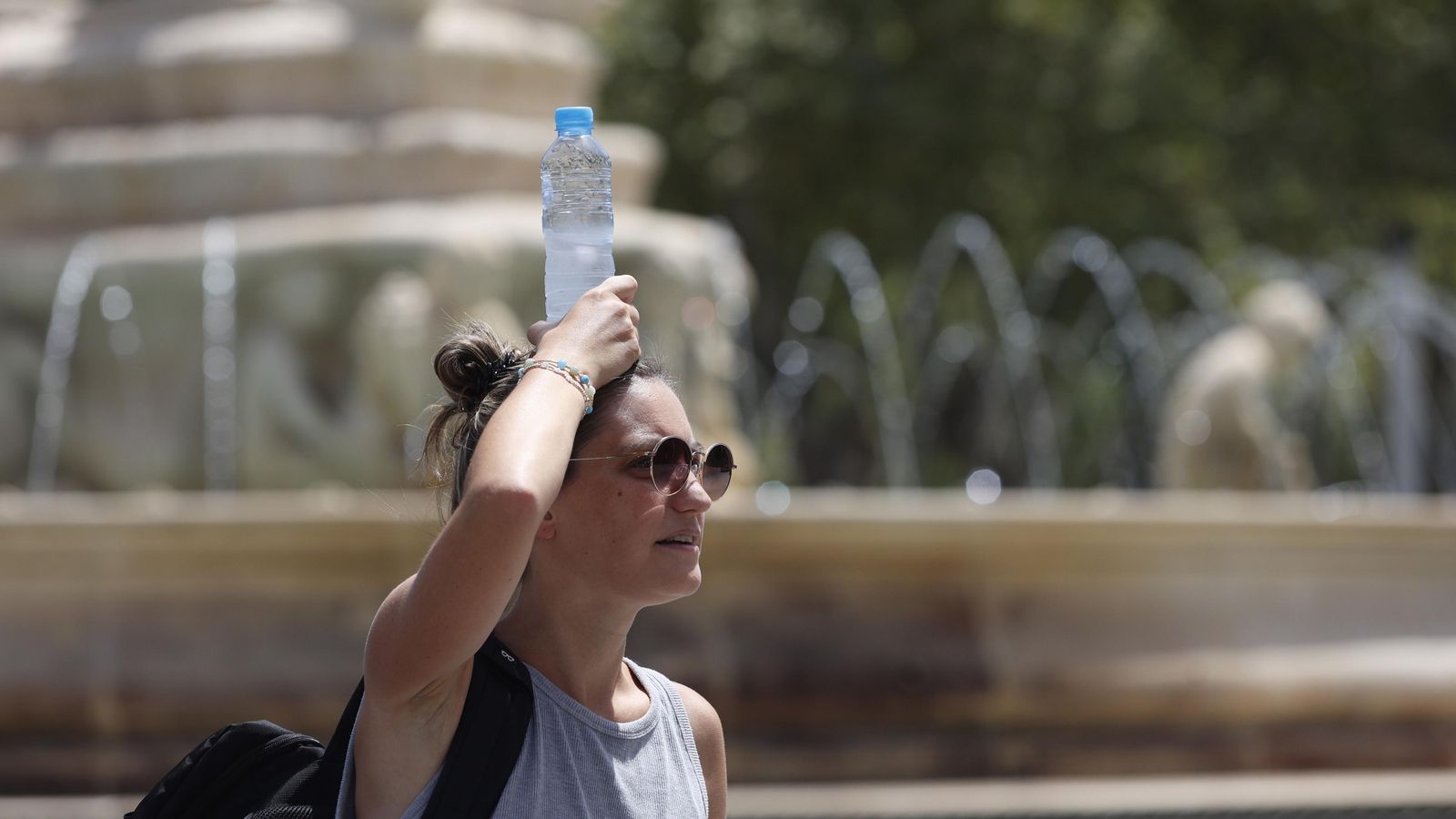 Una mujer se trata de refrescar con una botilla de agua fía sobre la cabeza.