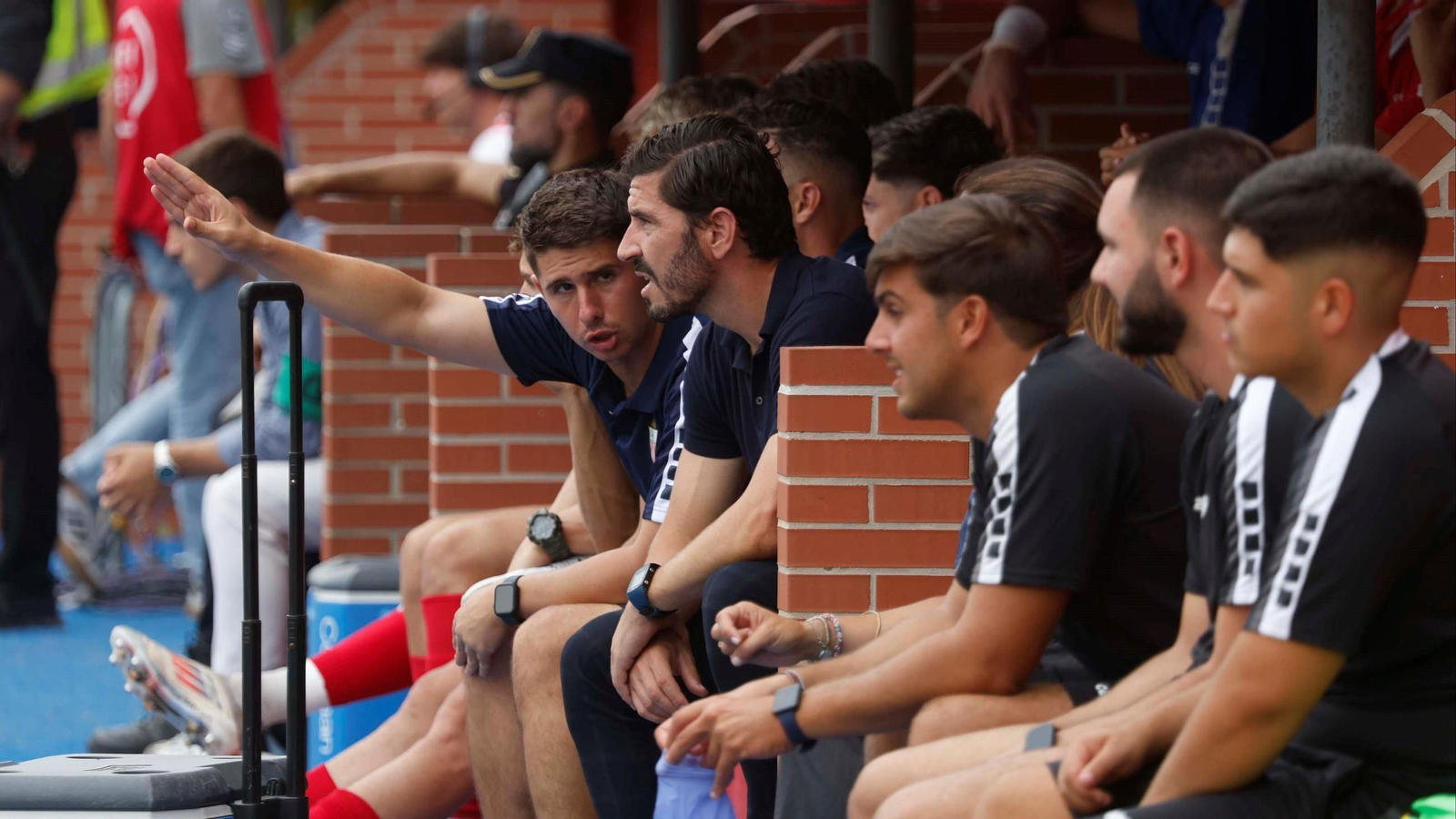 Javi Vázquez escucha a uno de sus asistentes en el banquillo del Nuevo Mirador.