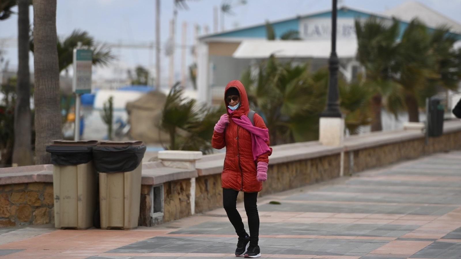 Una viandante, en el paseo marítimo de La Carihuela con fuertes rachas de viento.
