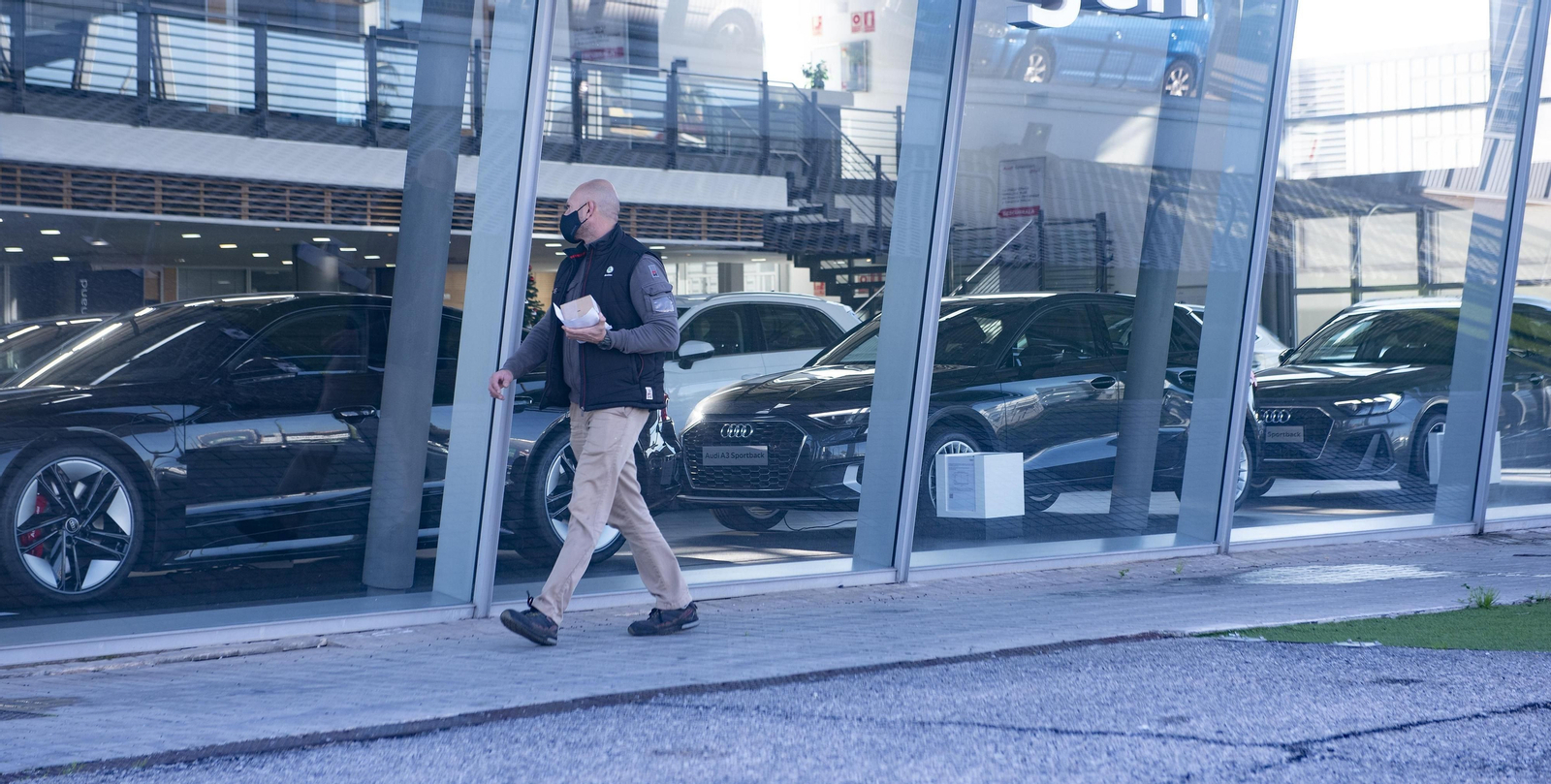 Un cliente pasa delante de un concesionario de coches.