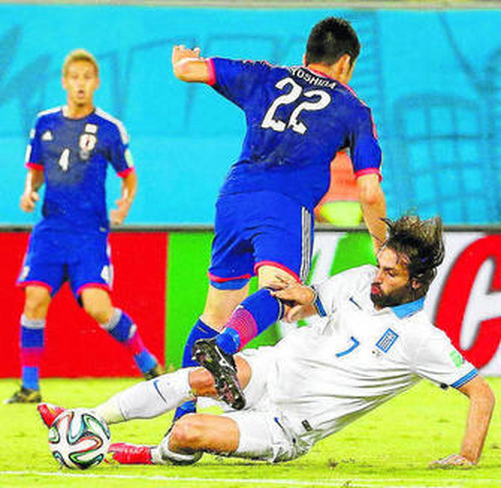 Samaras le roba el balón a Yoshida a ras de hierba.