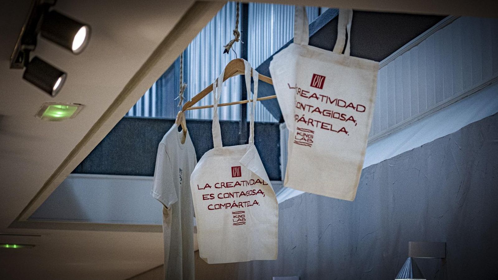 Bolsas de tela colgadas con el lema 'La creatividad es contagiosa, compártela'.
