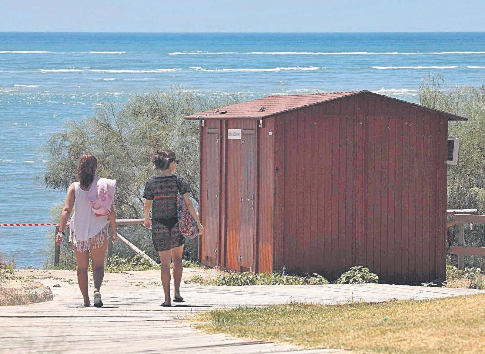 Dos mujeres caminan hacia la playa para tomar un baño.