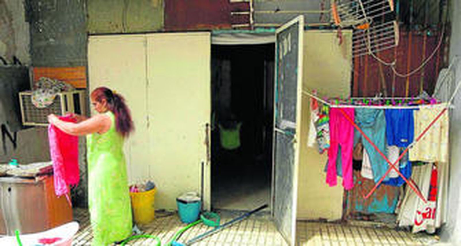 Una mujer lava la ropa en una chabola en las Tres Mil Viviendas.