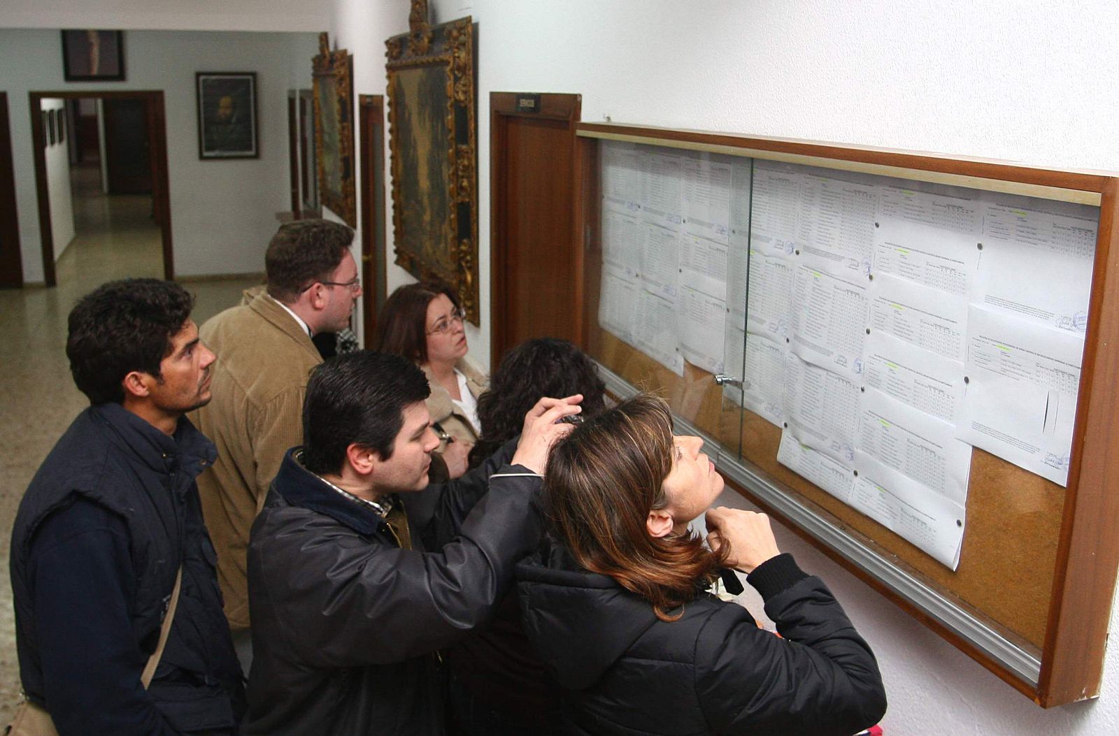Padres y madres consultan las listas de admitidos en un centro escolar.