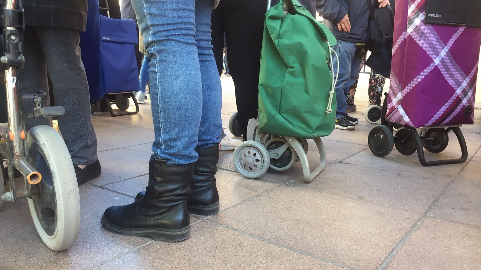 Personas en la cola, con sus carros de la compra.