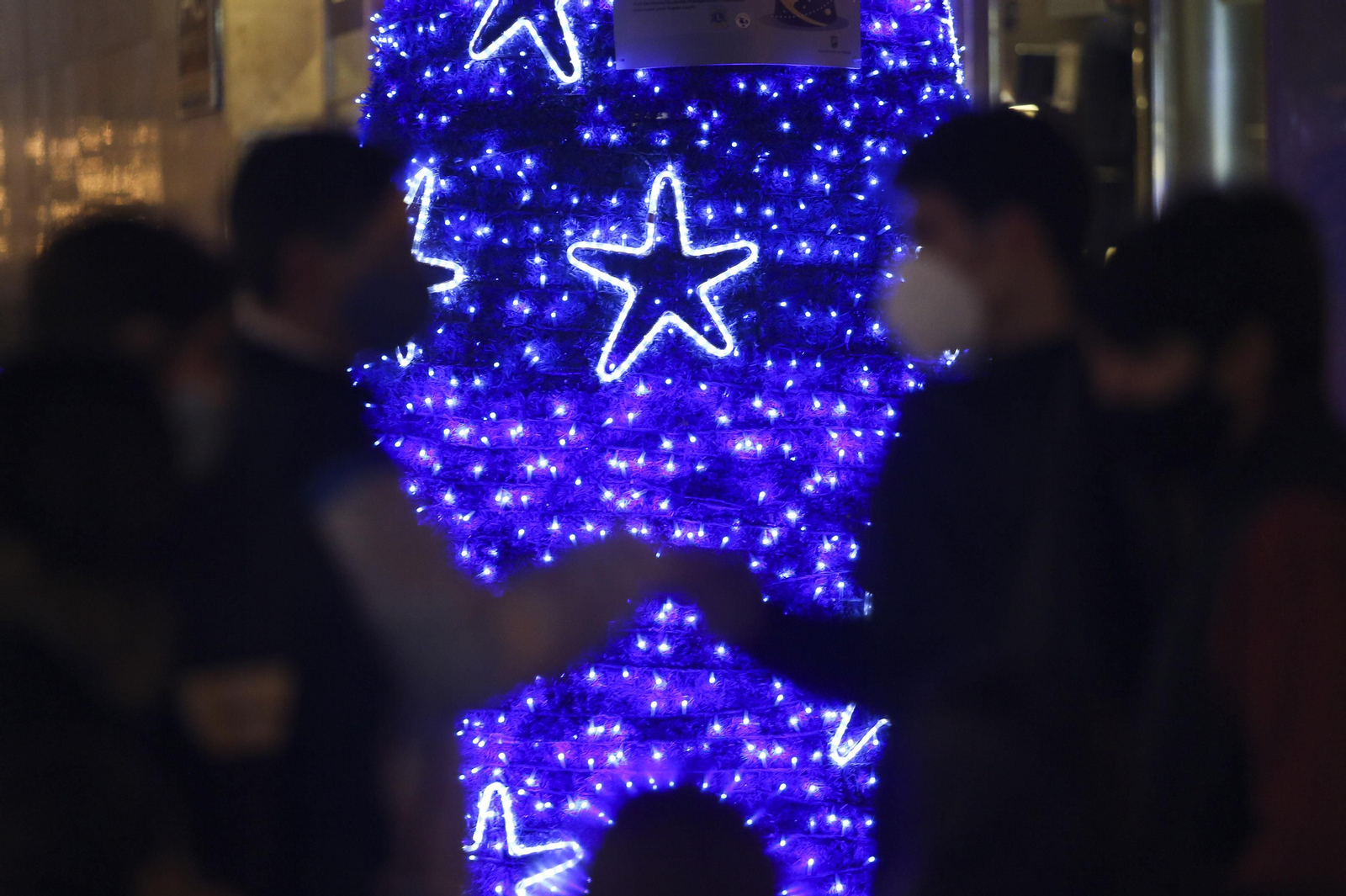 Dos amigos se saludan junto a un árbol navideño.