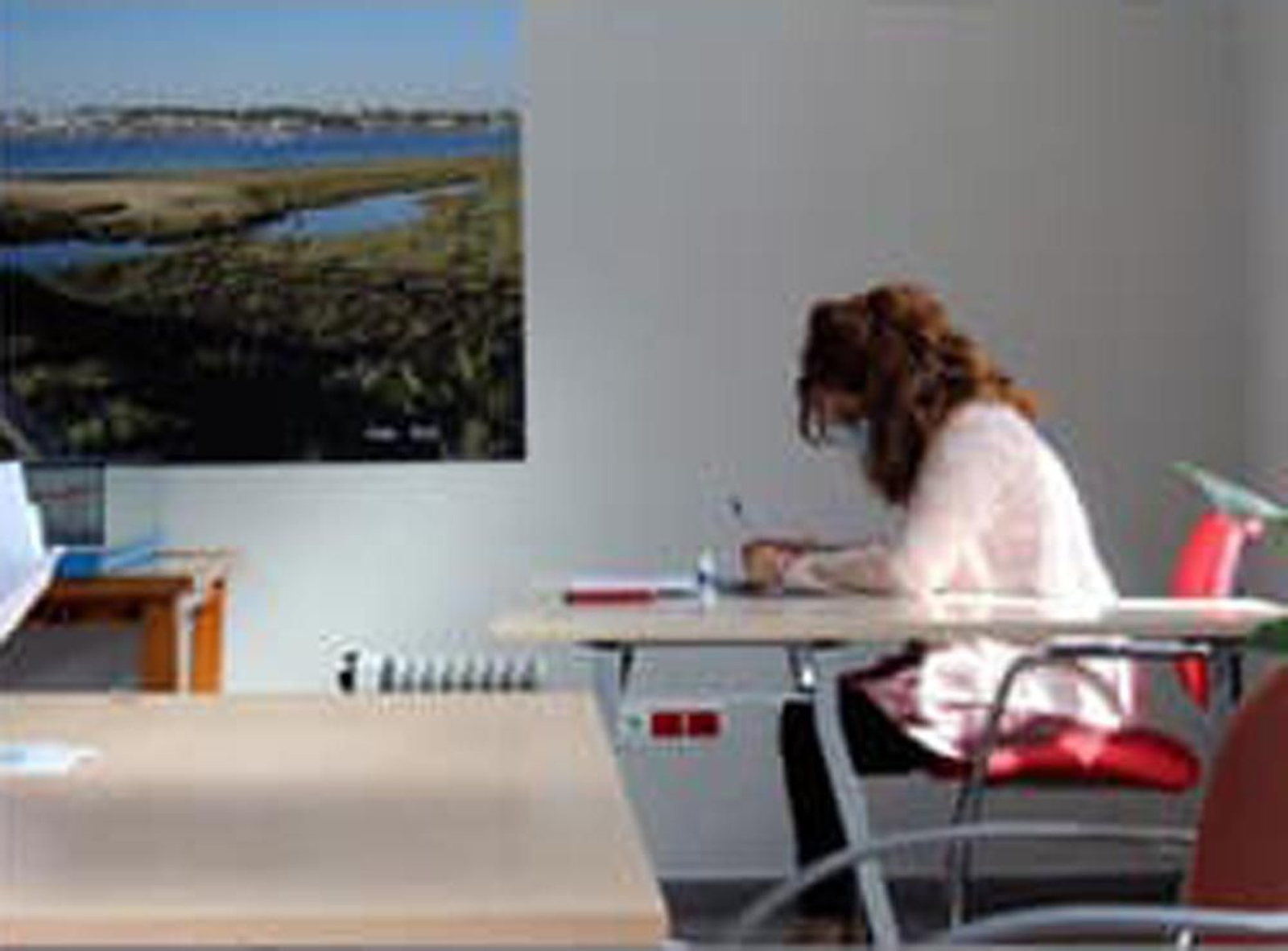Una joven en la sala de estudio de El Rompido, con parte de una de las fotografías que decoraban sus paredes al fondo