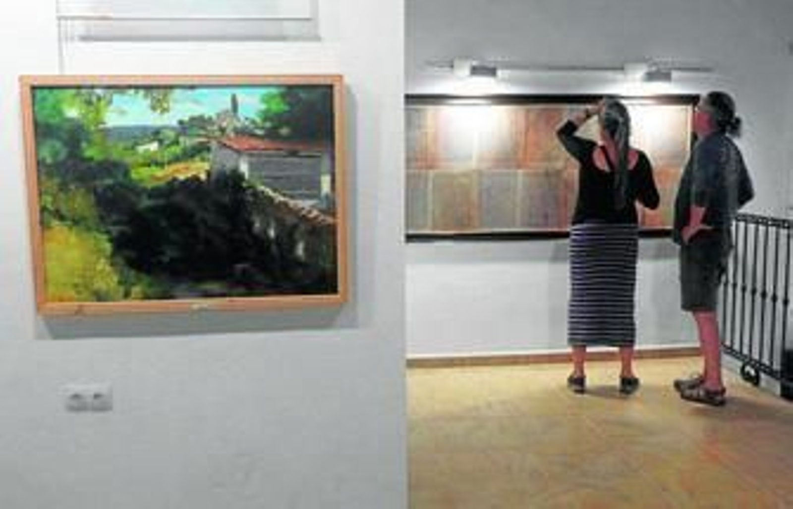 Una pareja mira detalladamente la reproducción del título de Villa de Cortelazor.