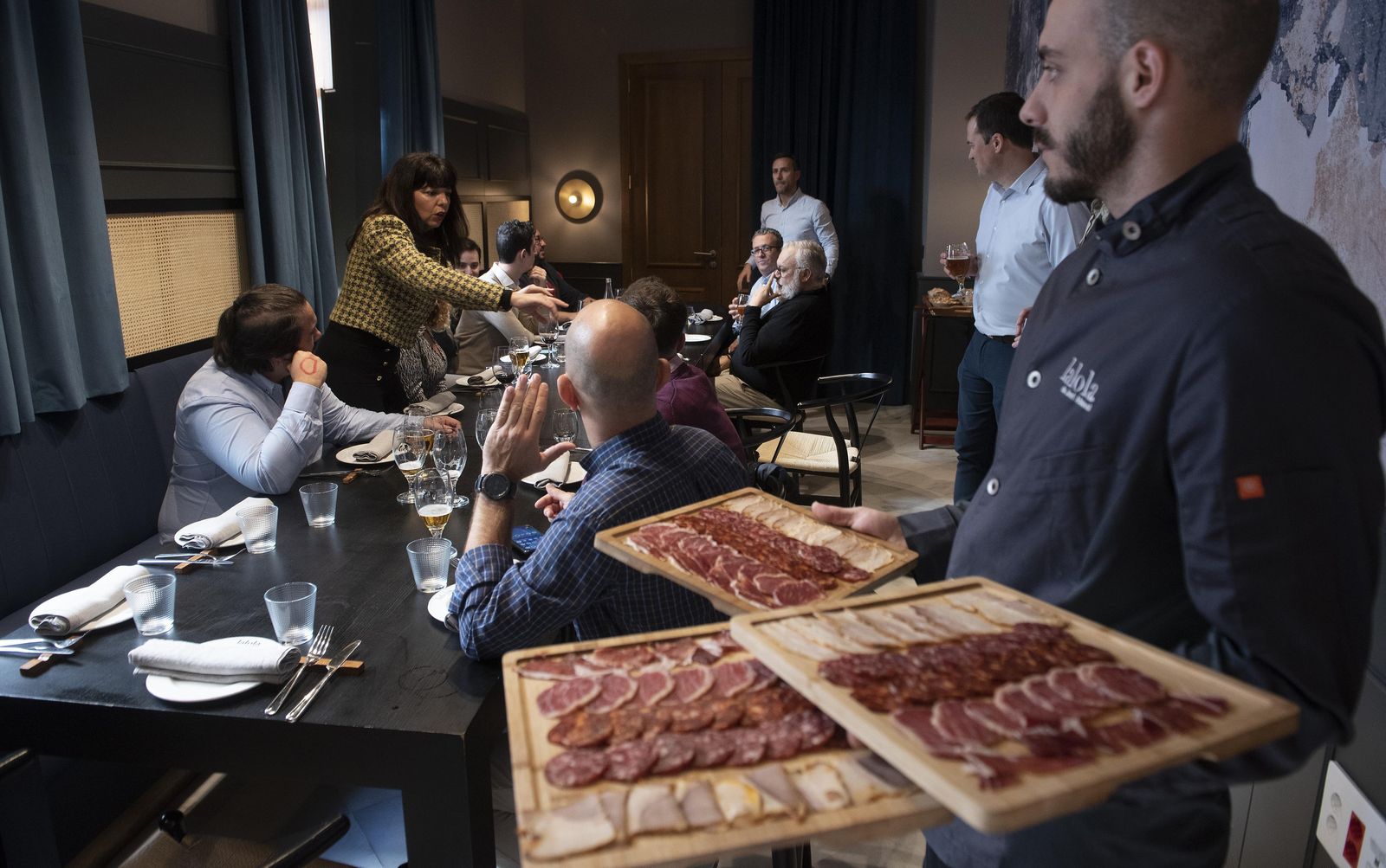 Un camarero sirve chacina para esta reunión en el restaurante La Lola.