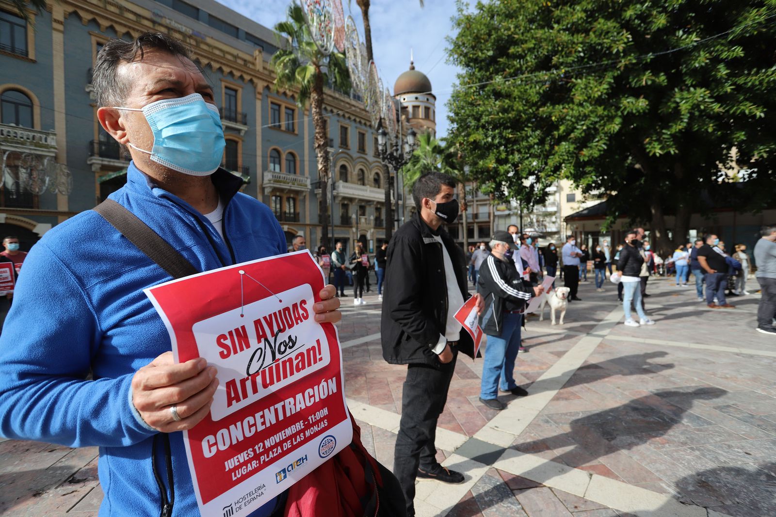 En primer término, uno de los hosteleros sosteniendo el cartel con el lema de la concentración, ayer en la plaza de Las Monjas.