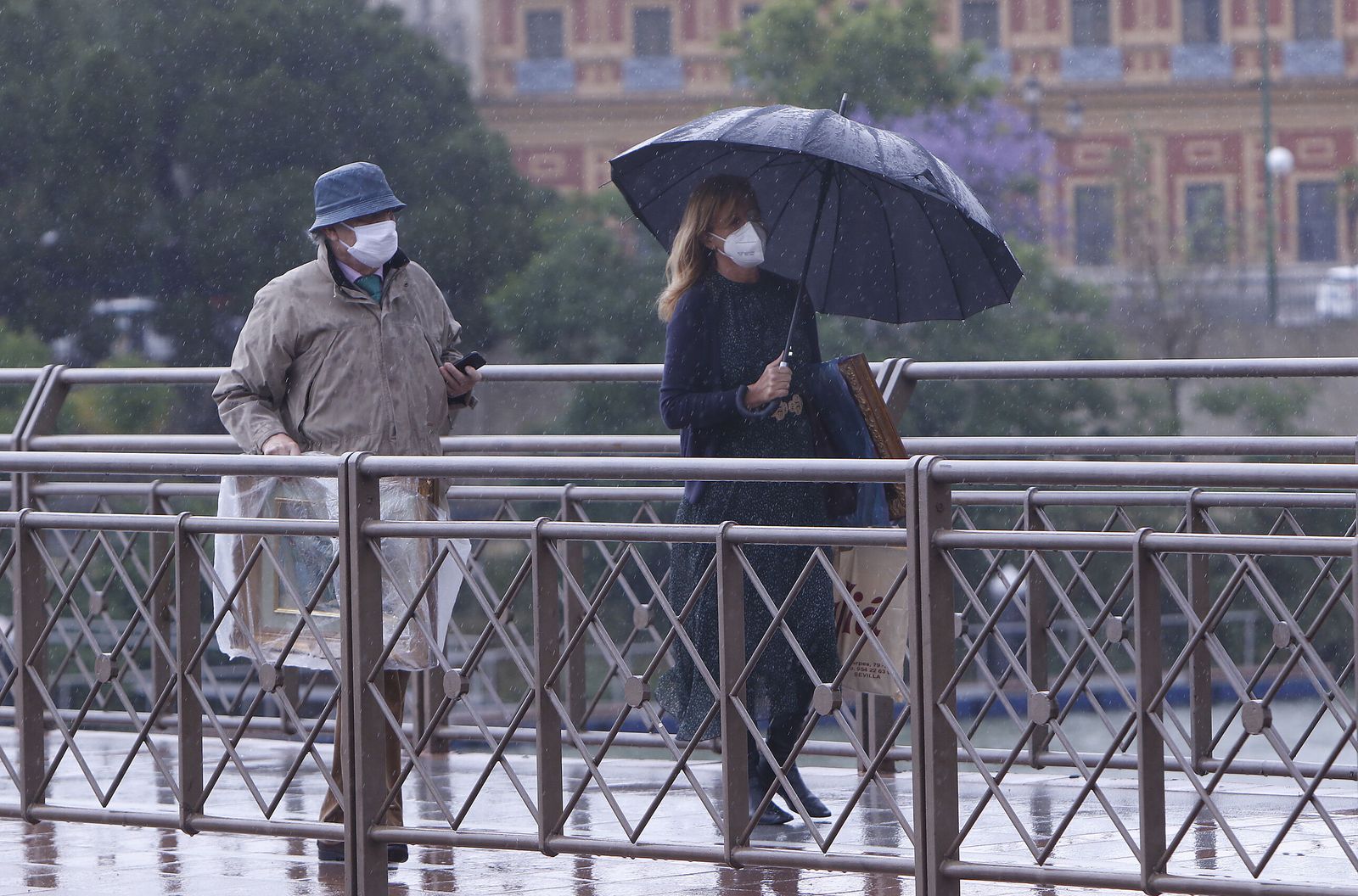 Dos personas se protegen de la lluvia en Sevilla.