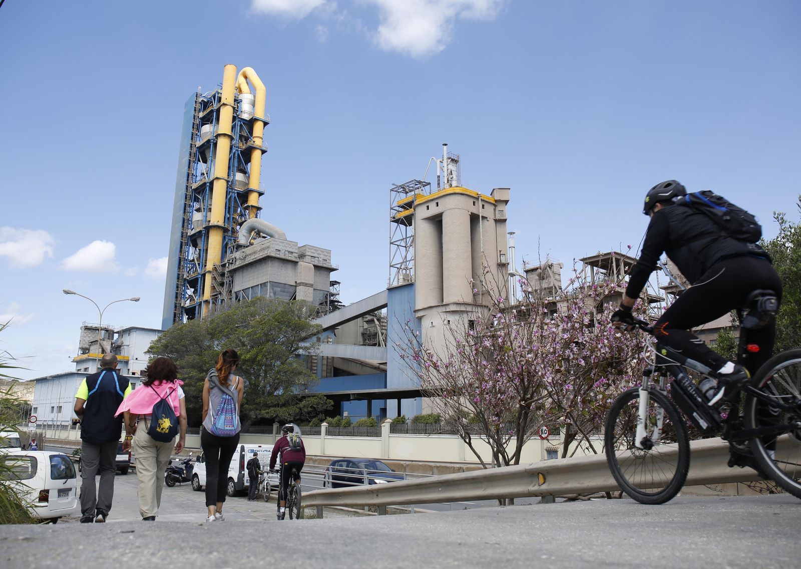 Varias personas pasan cerca de la fábrica de cemento de La Araña.