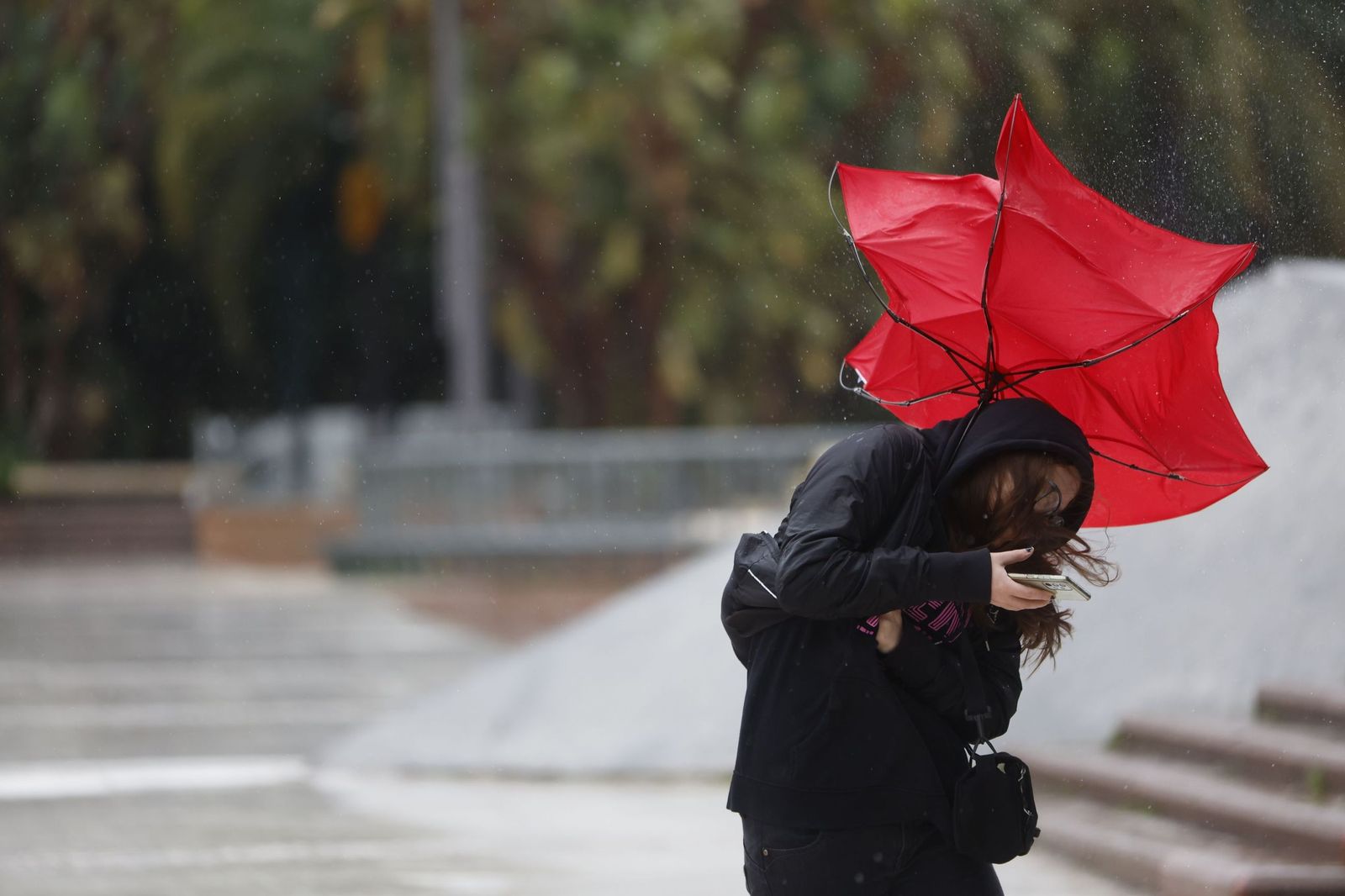 Una mujer lucha contra el fuerte viento  que se registra en Andalucía.