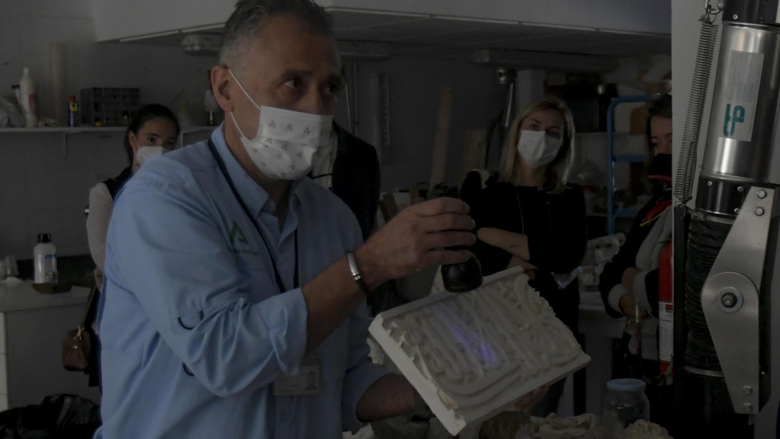 Explicación de unos de los restauradores a los asistentes en la oscuridad para evitar dañar la pieza