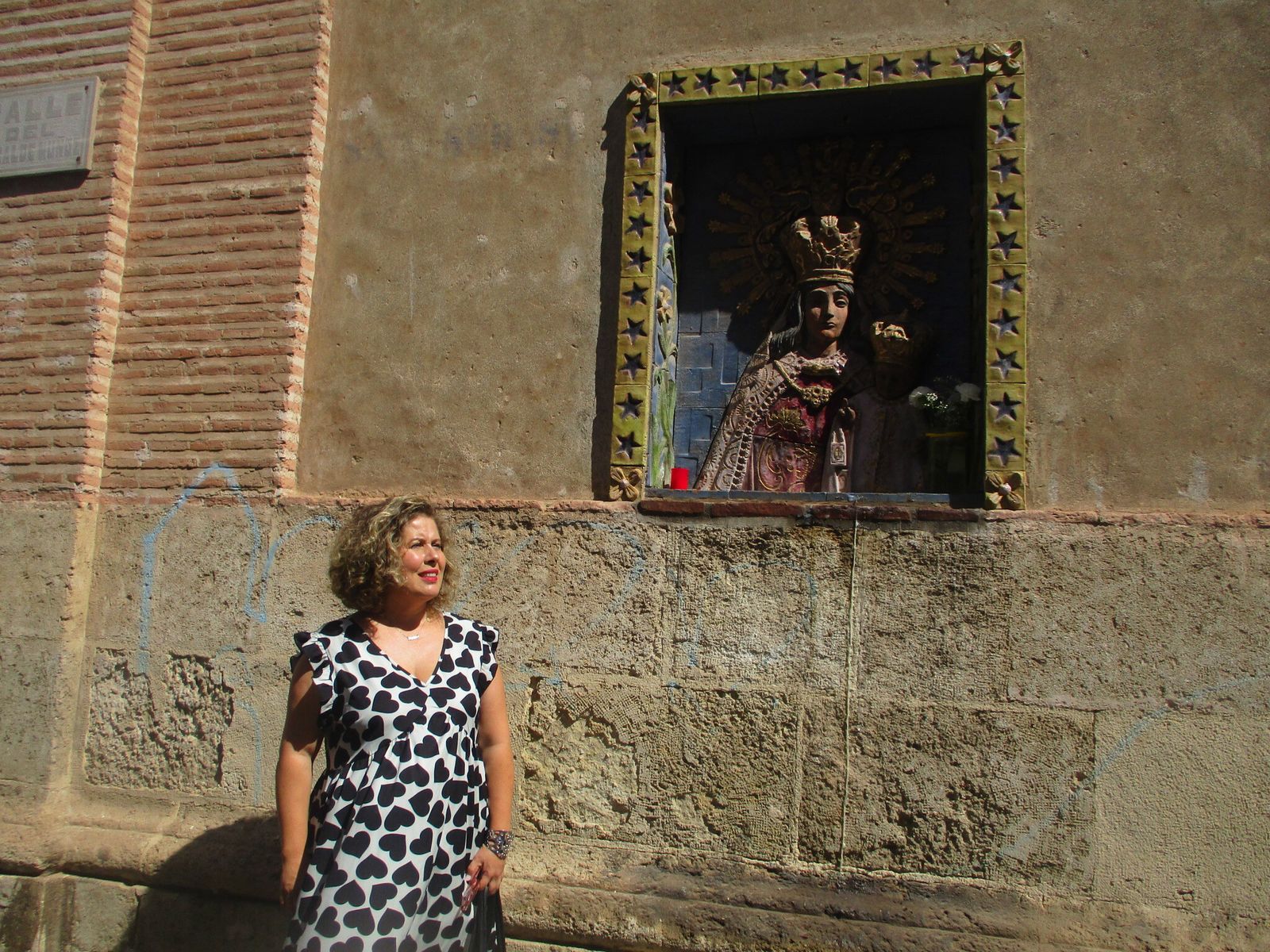 Mar Esteban ante el relieve de la Virgen del Carmen de las Huertas situado en un muro lateral de la iglesia de San Sebastián.