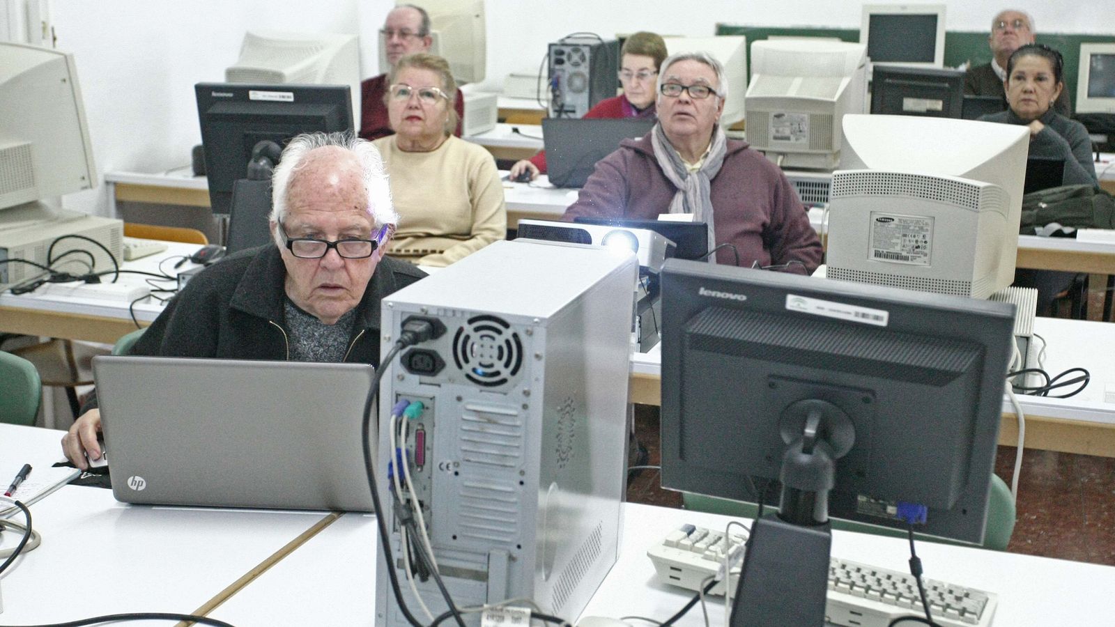 Gente mayor aprendiendo informática en un aula.