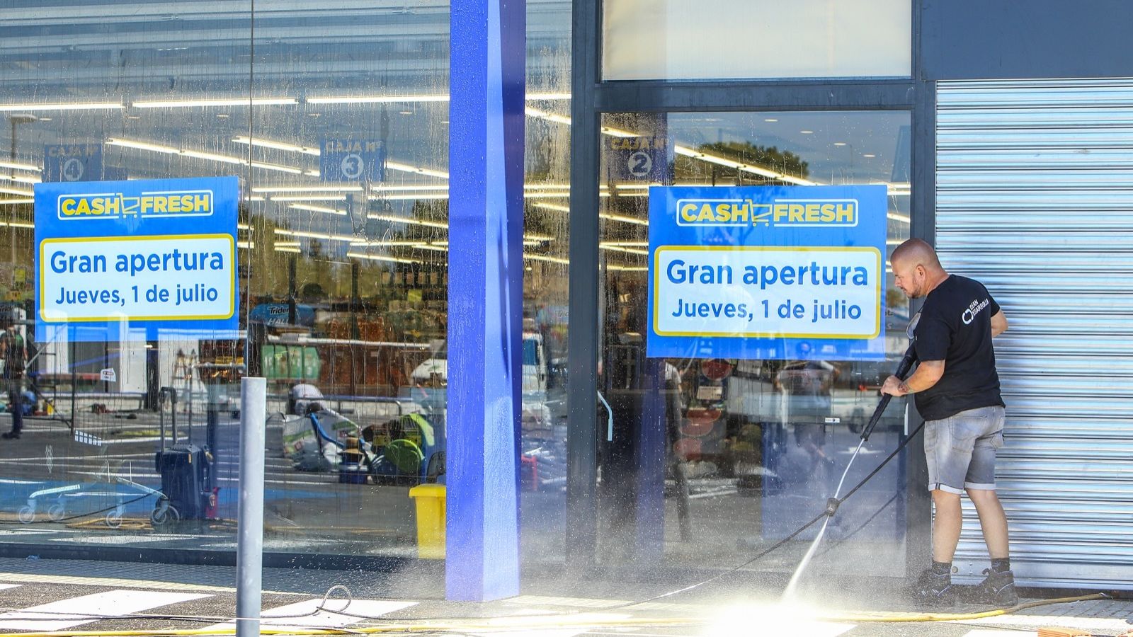 Un trabajador realiza labores de limpieza en el exterior de la tienda de Cash Fresh.