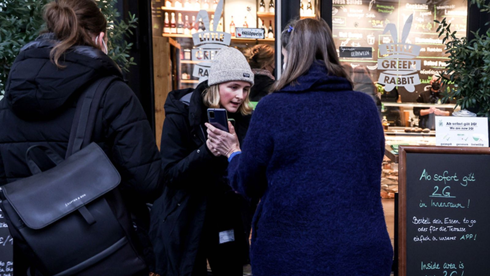 Una empleada de un restaurante berlinés chequea los certificados de vacunación de dos clientas.