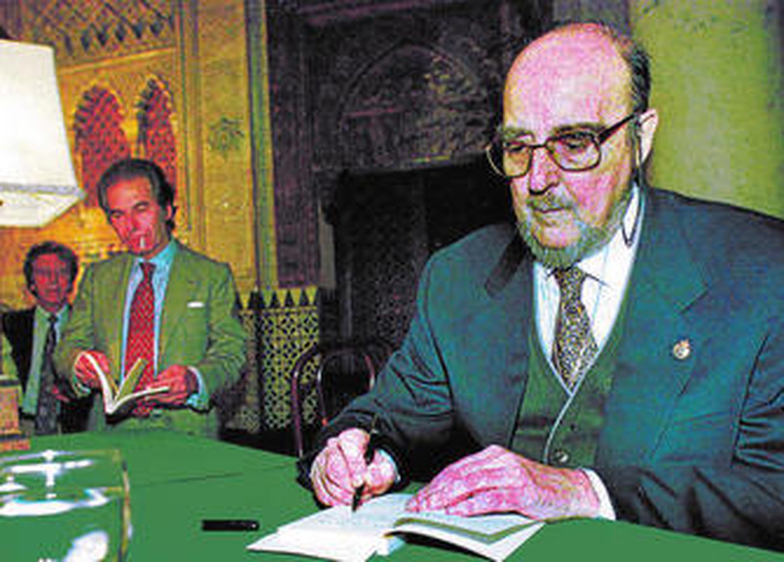 El escritor Fernando Quiñones firma un ejemplar de uno de sus libros ante el torero Rafael de Paula.