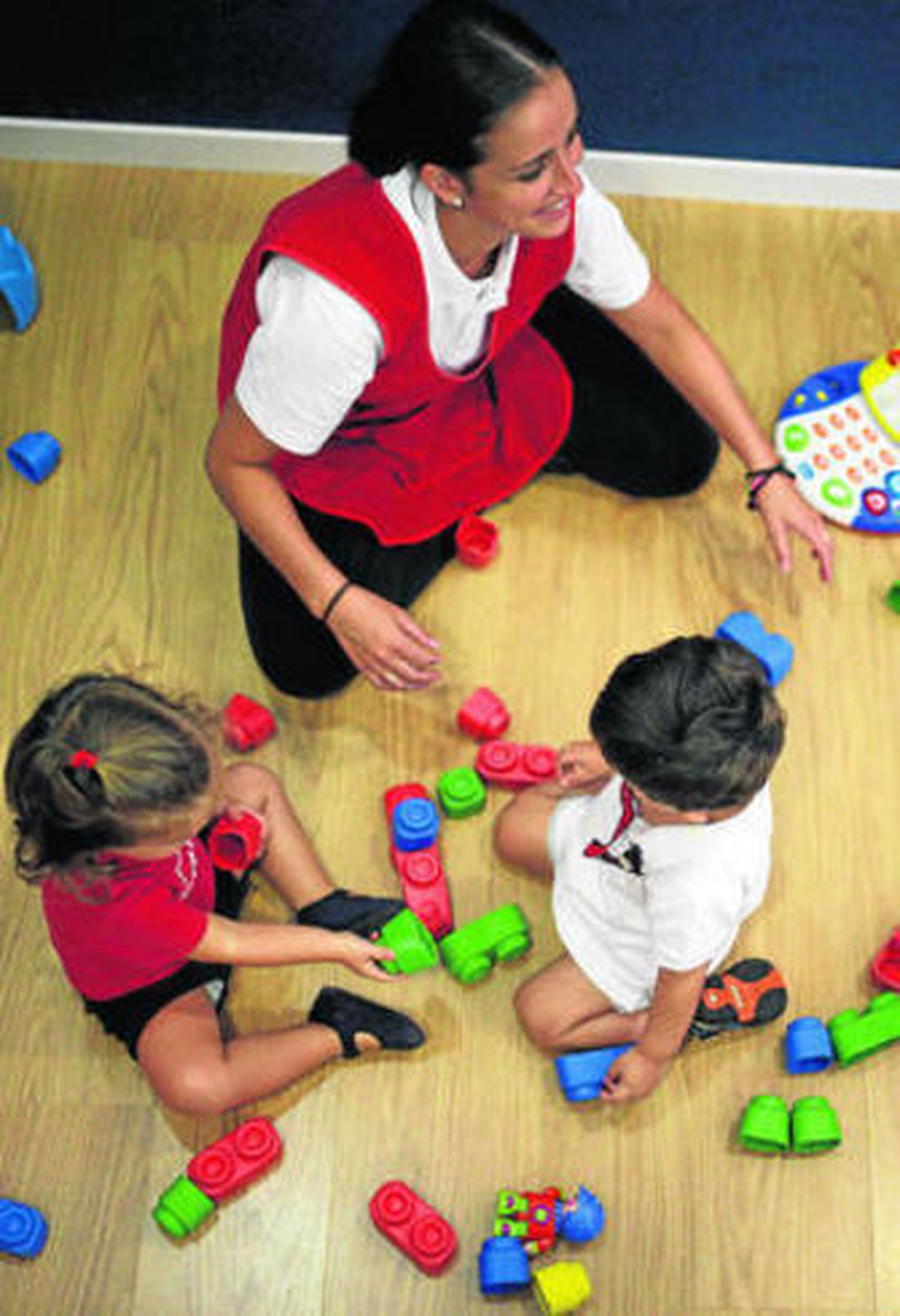 La maestra de una guardería atiende a una pareja de niños.