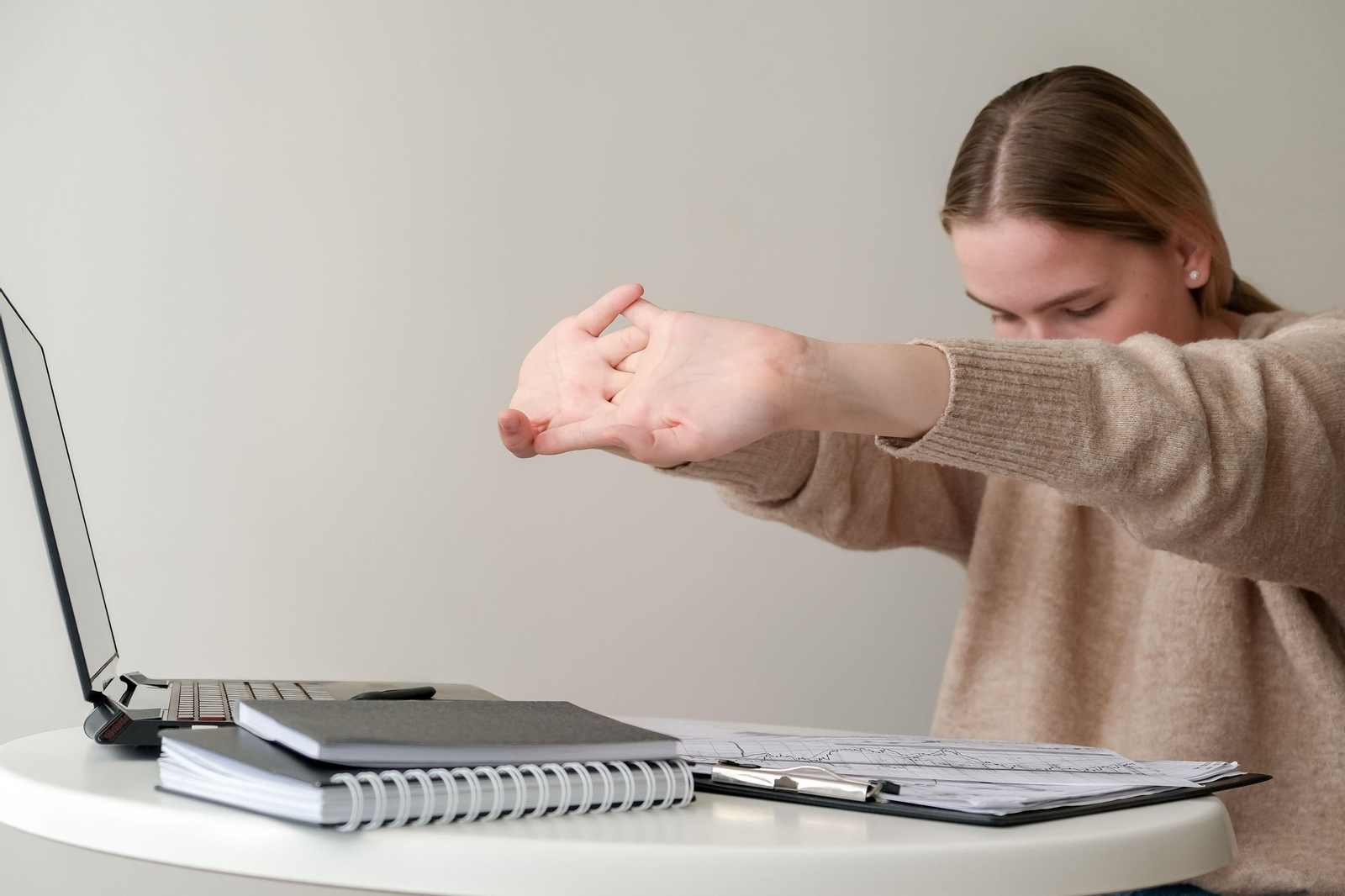 Una mujer se estira mientras trabaja con el ordenador.