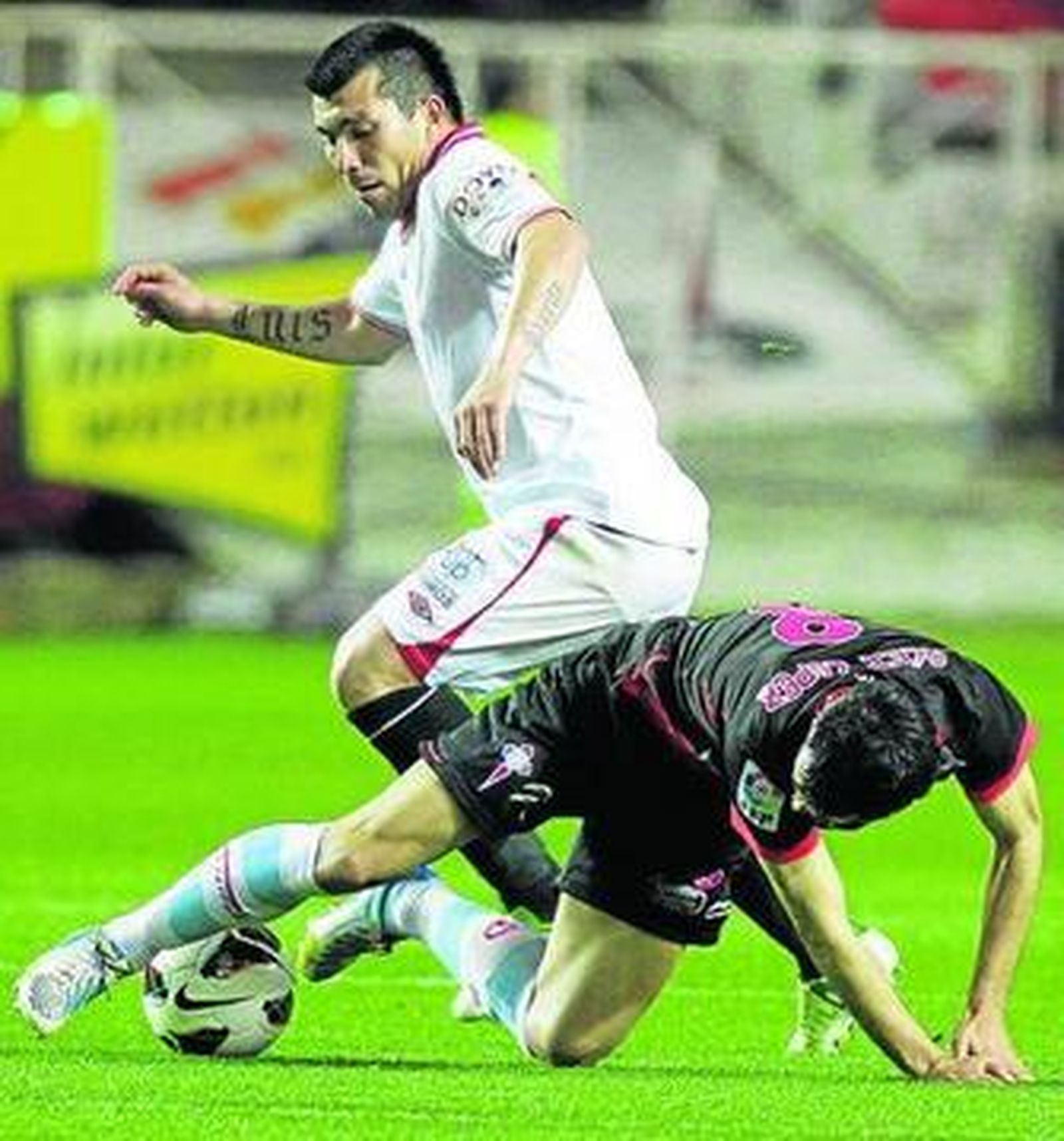 Álex López, desde el suelo, mantiene el balón ante Medel.