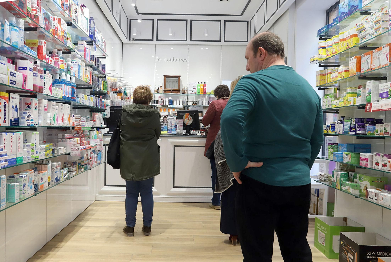 Varias personas hacen cola en una farmacia de la capital onubense.