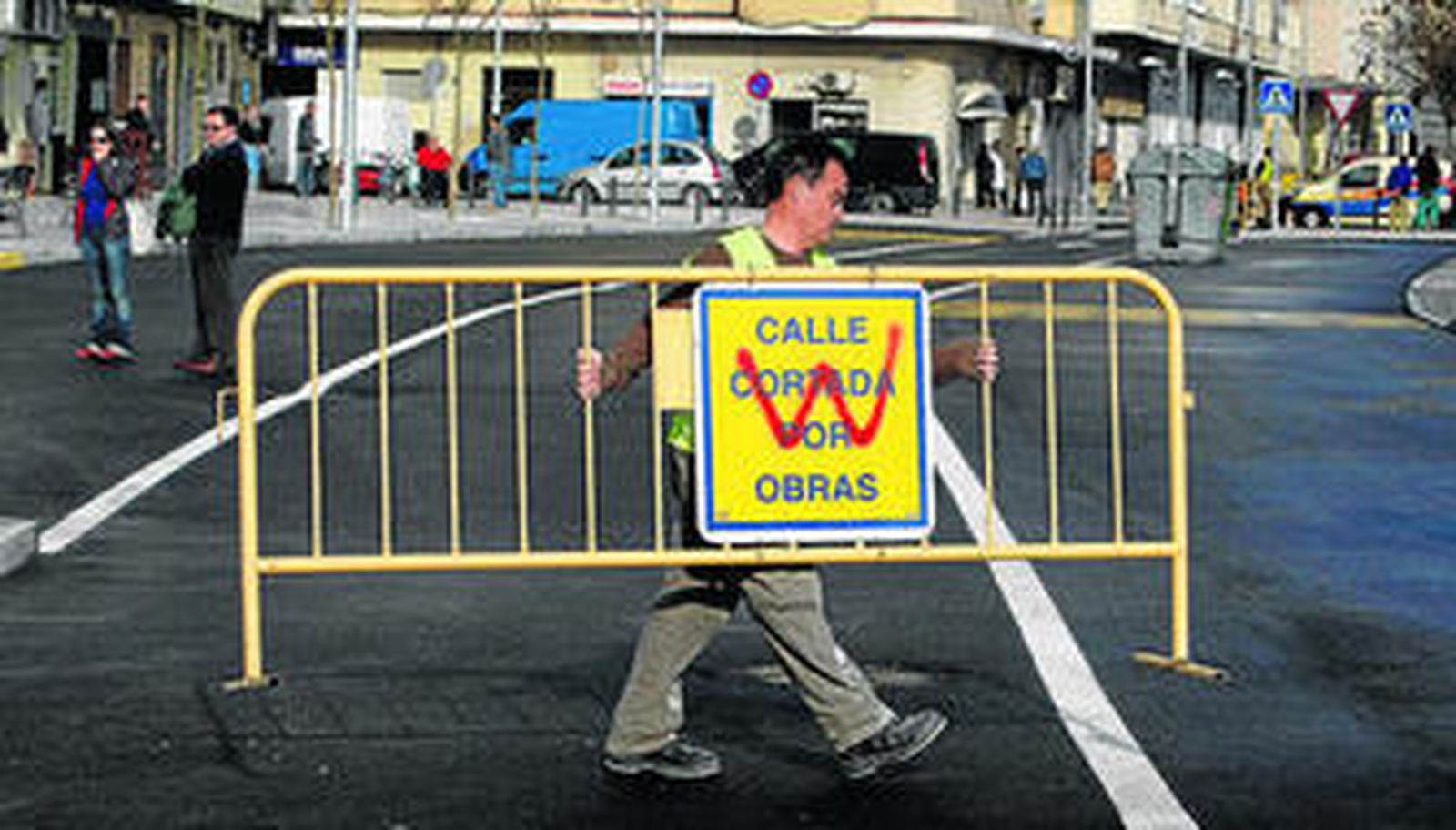Un trabajador retira la valla que cortaba el tráfico durante las obras.