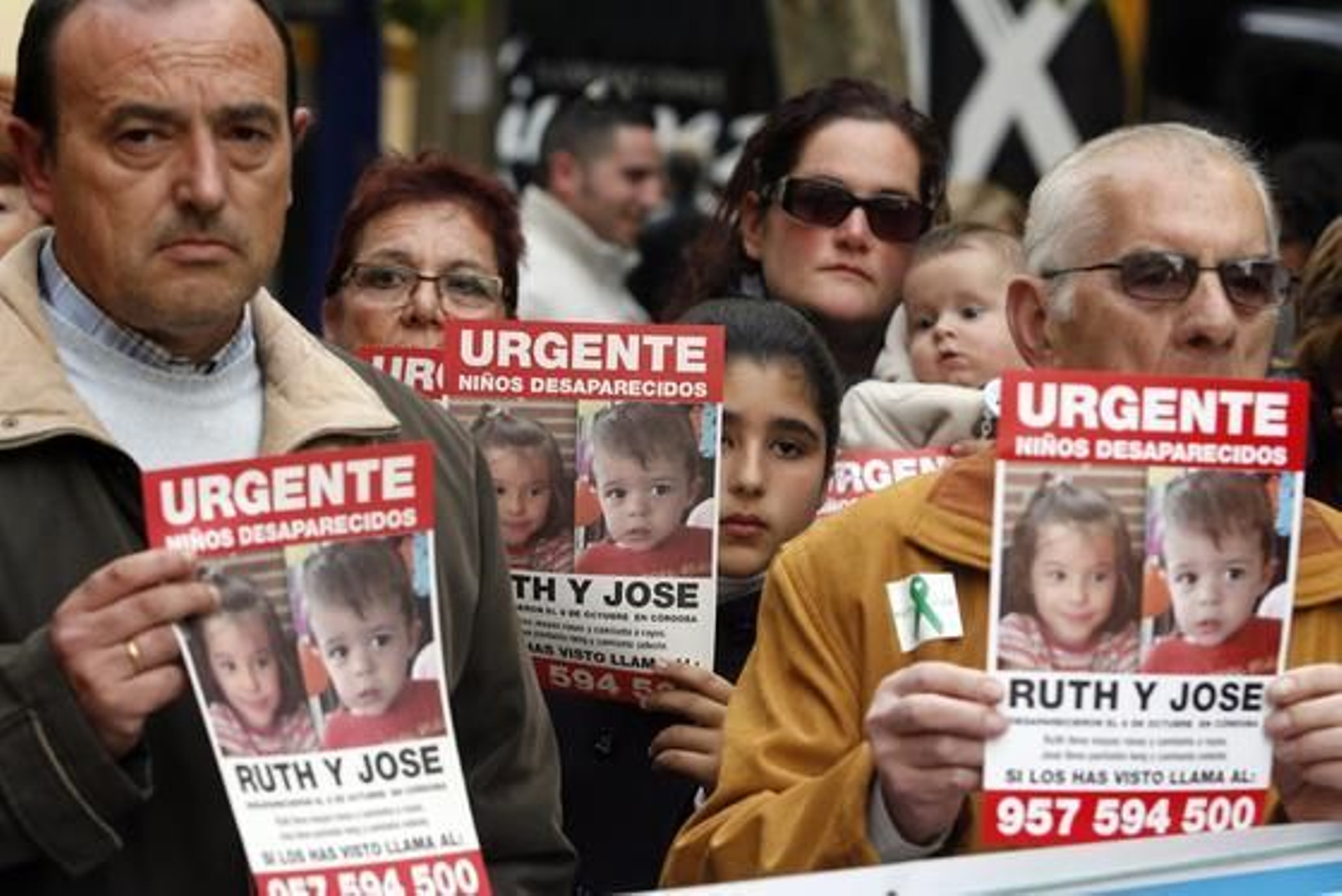 Ciudadanos afectados posan con carteles de los pequeños desaparecidos.